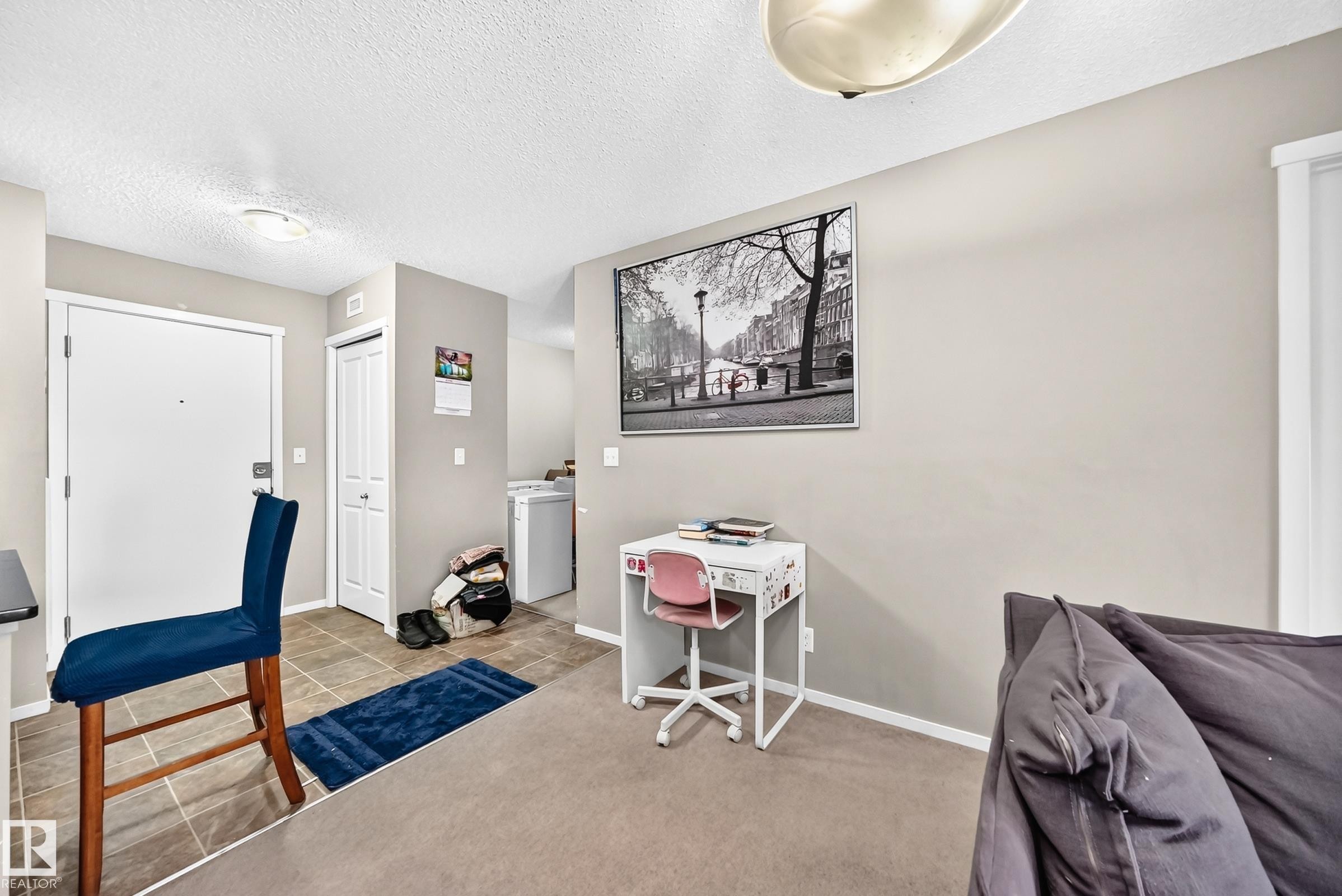 Entry area with tile flooring opening to a carpeted living space - #417 1510 Watt Dr Sw, Edmonton, AB - Indoor