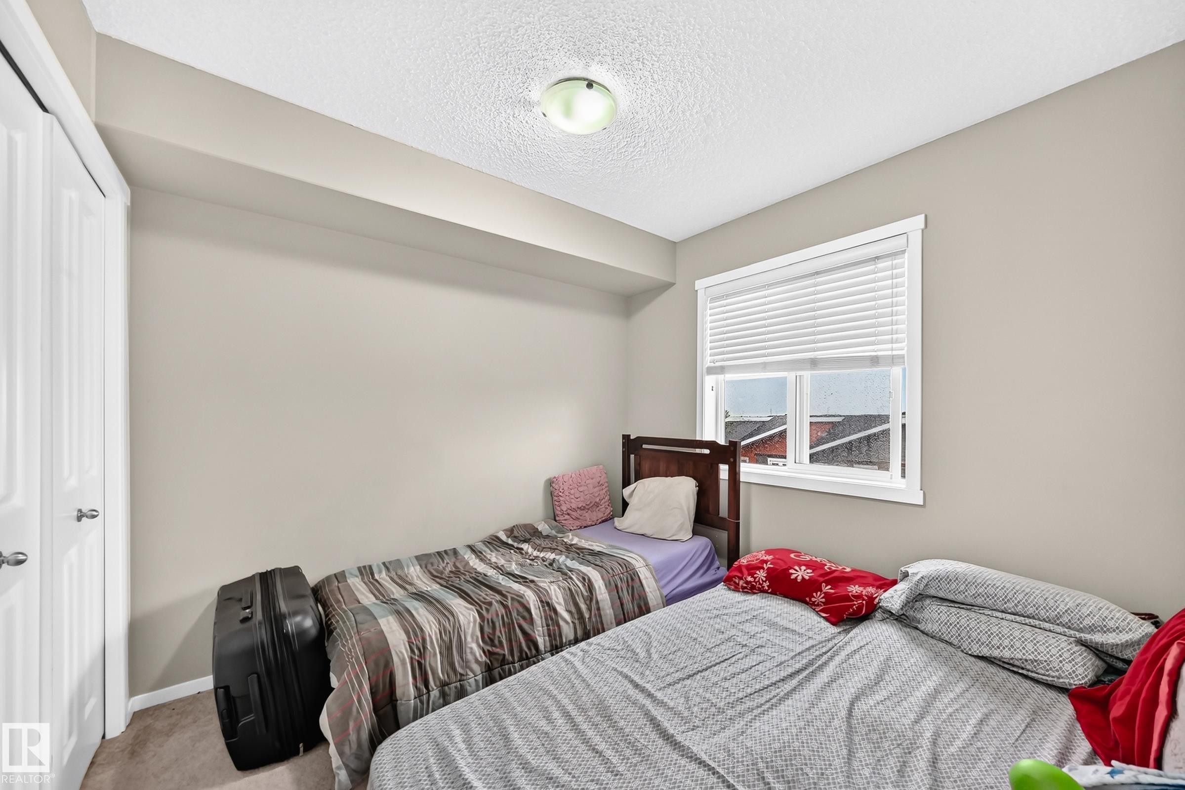 Bedroom with neutral wall tones and a window with white blinds - #417 1510 Watt Dr Sw, Edmonton, AB - Indoor Photo Showing Bedroom