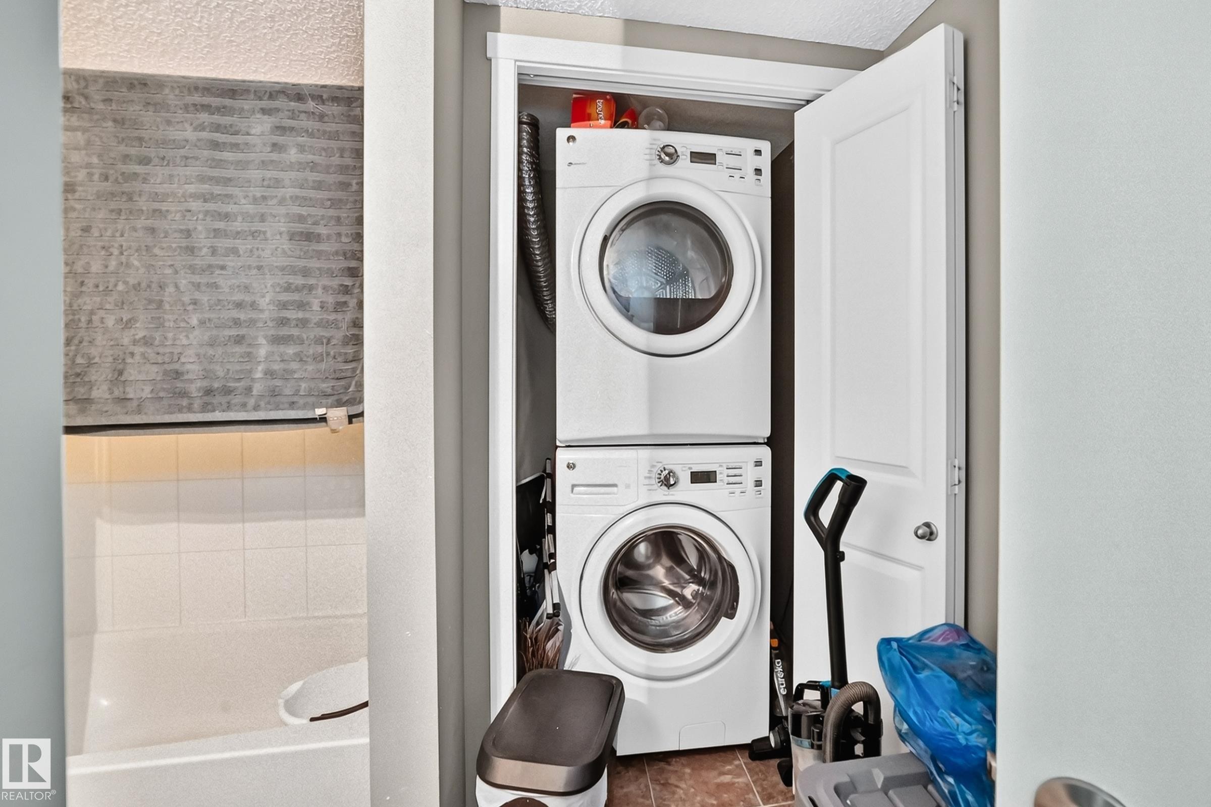Laundry closet featuring a stacked white washer and dryer unit with a tiled floor - #417 1510 Watt Dr Sw, Edmonton, AB - Indoor Photo Showing Laundry Room