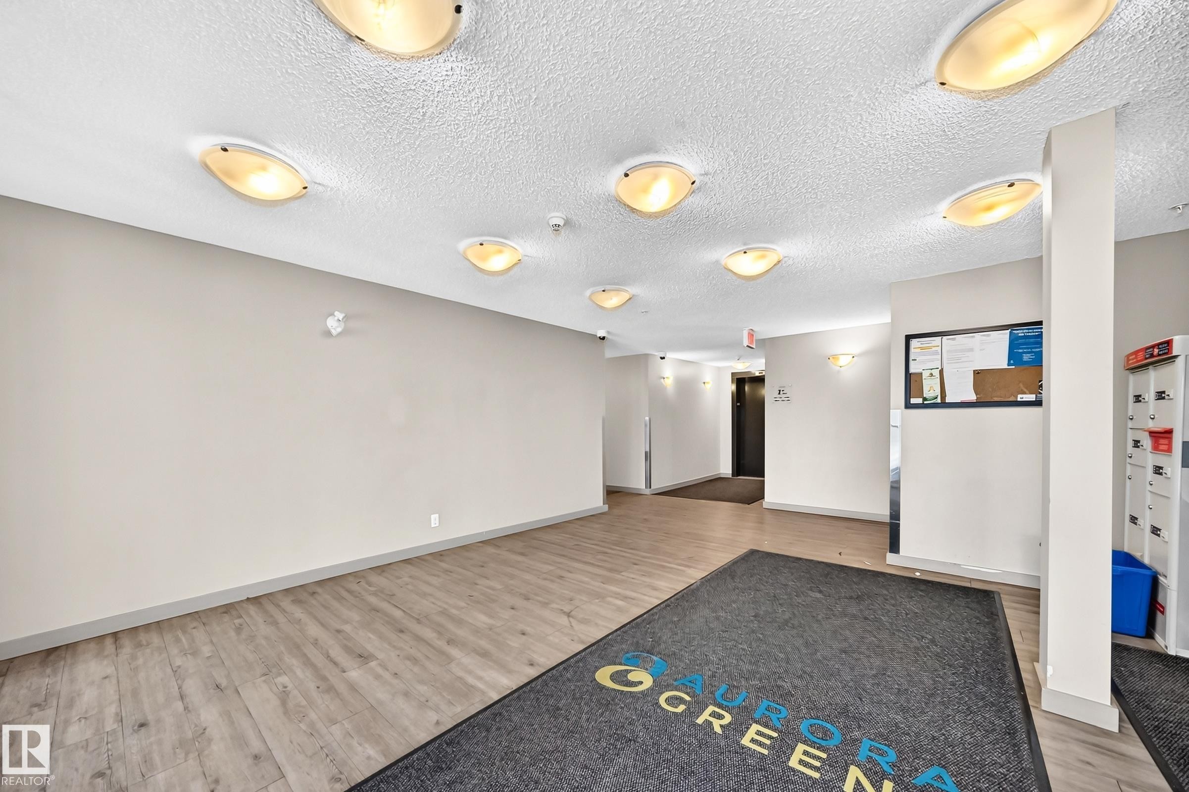 Entryway featuring wood-finish flooring, a textured ceiling, and multiple flush-mount ceiling lights - #417 1510 Watt Dr Sw, Edmonton, AB - Indoor Photo Showing Other Room