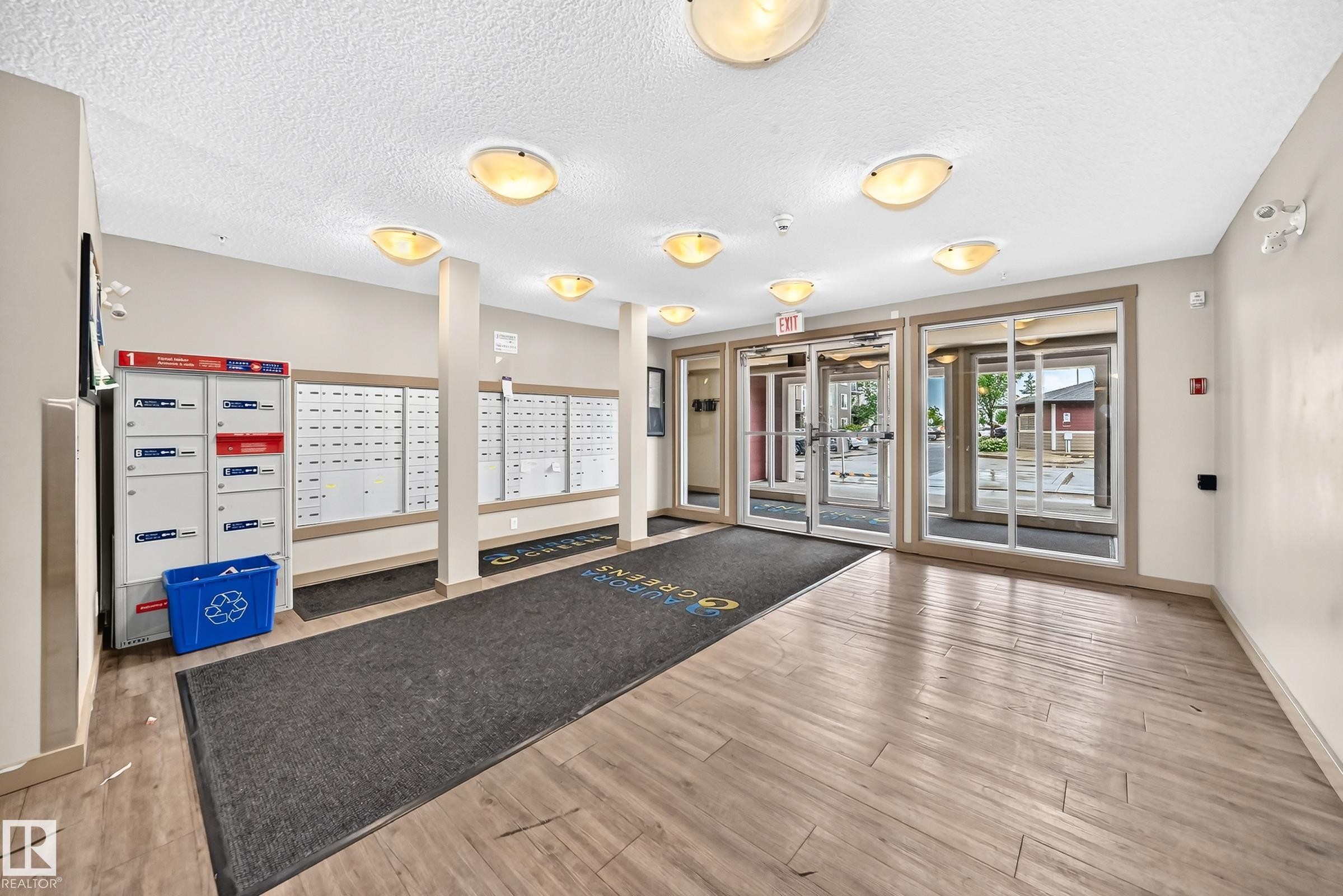 Building entrance featuring wood-finish flooring and multiple flush-mount light fixtures - #417 1510 Watt Dr Sw, Edmonton, AB - Indoor Photo Showing Other Room
