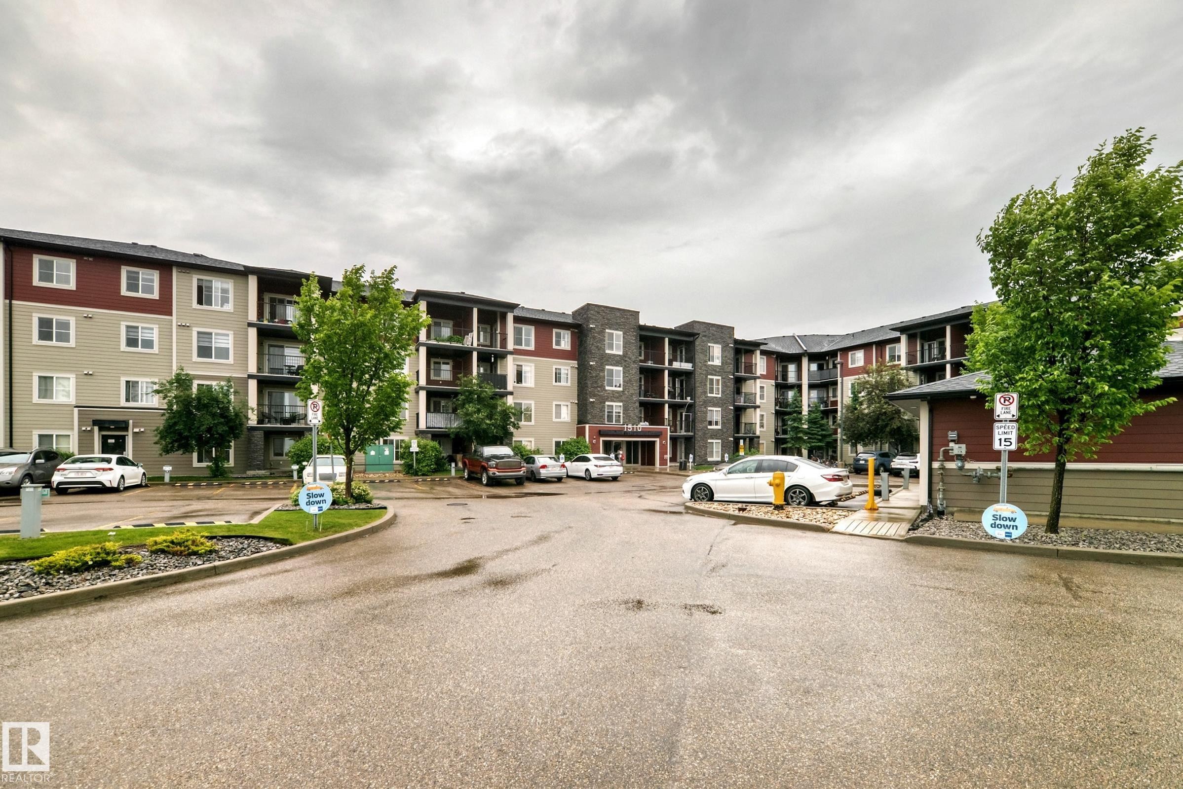 Multi-story building featuring a facade with dark red and light grey siding, multiple balconies with dark railings, and numerous windows - #417 1510 Watt Dr Sw, Edmonton, AB - Outdoor With Balcony With Facade