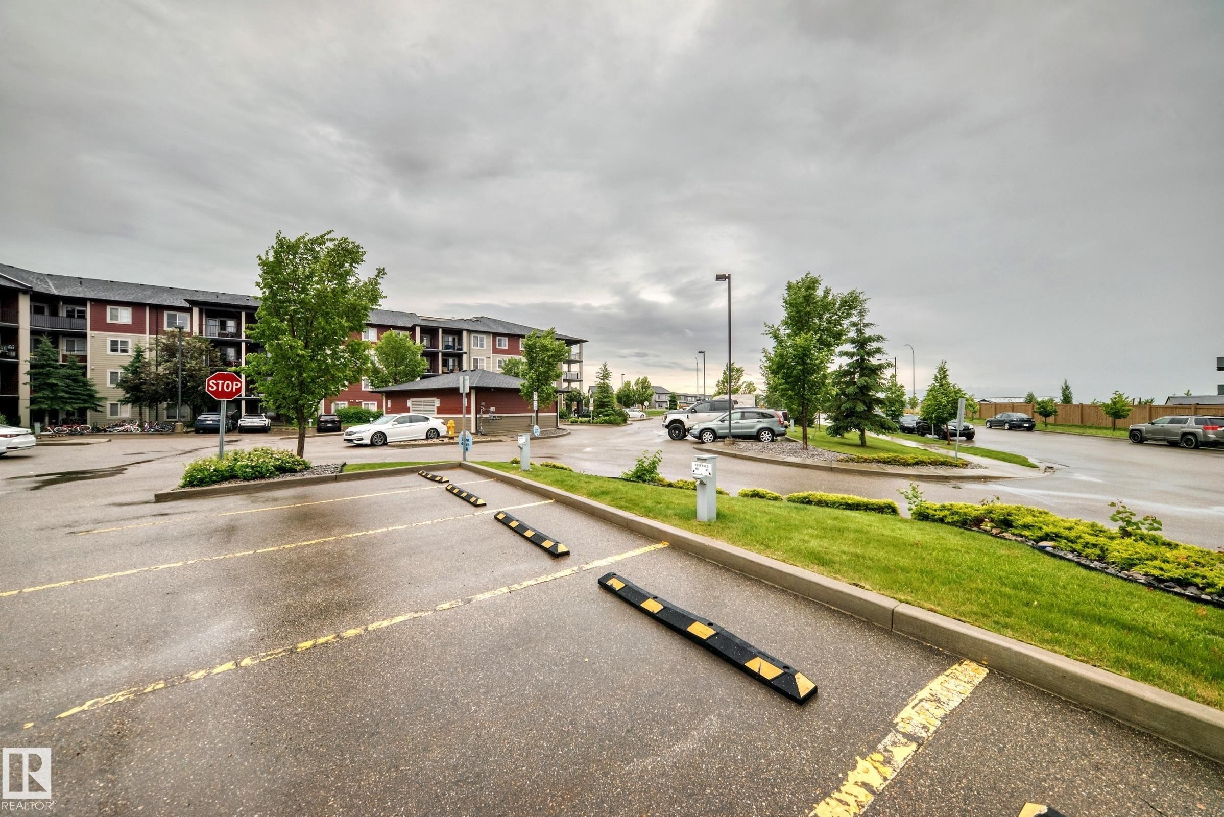 Multi-story residential building featuring red and beige siding, dark-framed balconies, and a dark roofline - #417 1510 Watt Dr Sw, Edmonton, AB - Outdoor