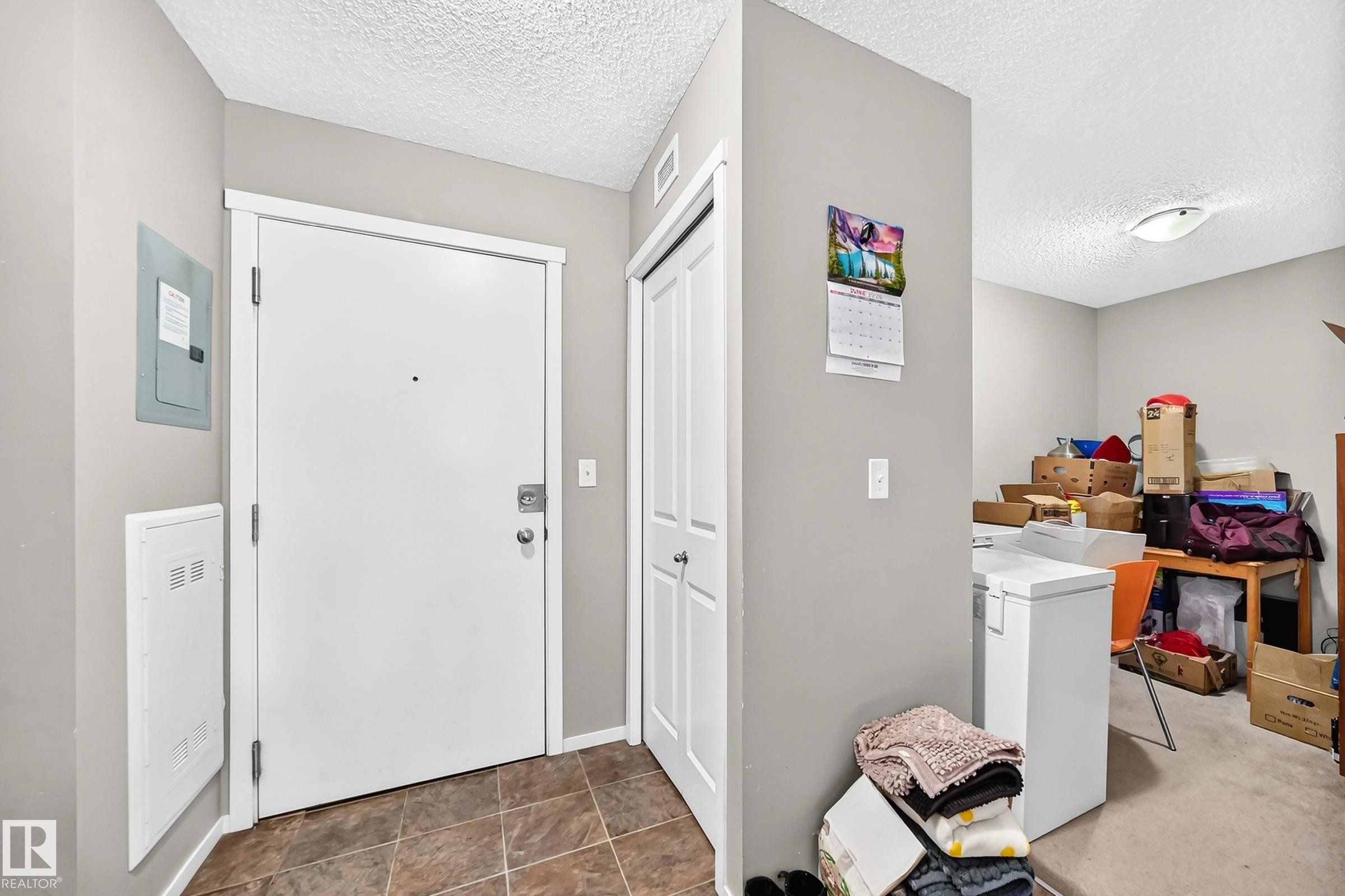 Entryway featuring tile flooring, a white entry door, and a built-in closet with bifold doors - #417 1510 Watt Dr Sw, Edmonton, AB - Indoor Photo Showing Other Room