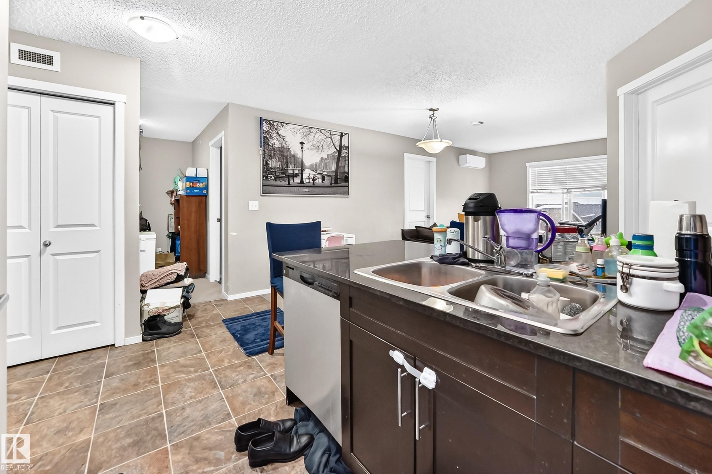 Kitchen island with a double basin stainless steel sink and dark countertop - #417 1510 Watt Dr Sw, Edmonton, AB - Indoor Photo Showing Kitchen With Double Sink