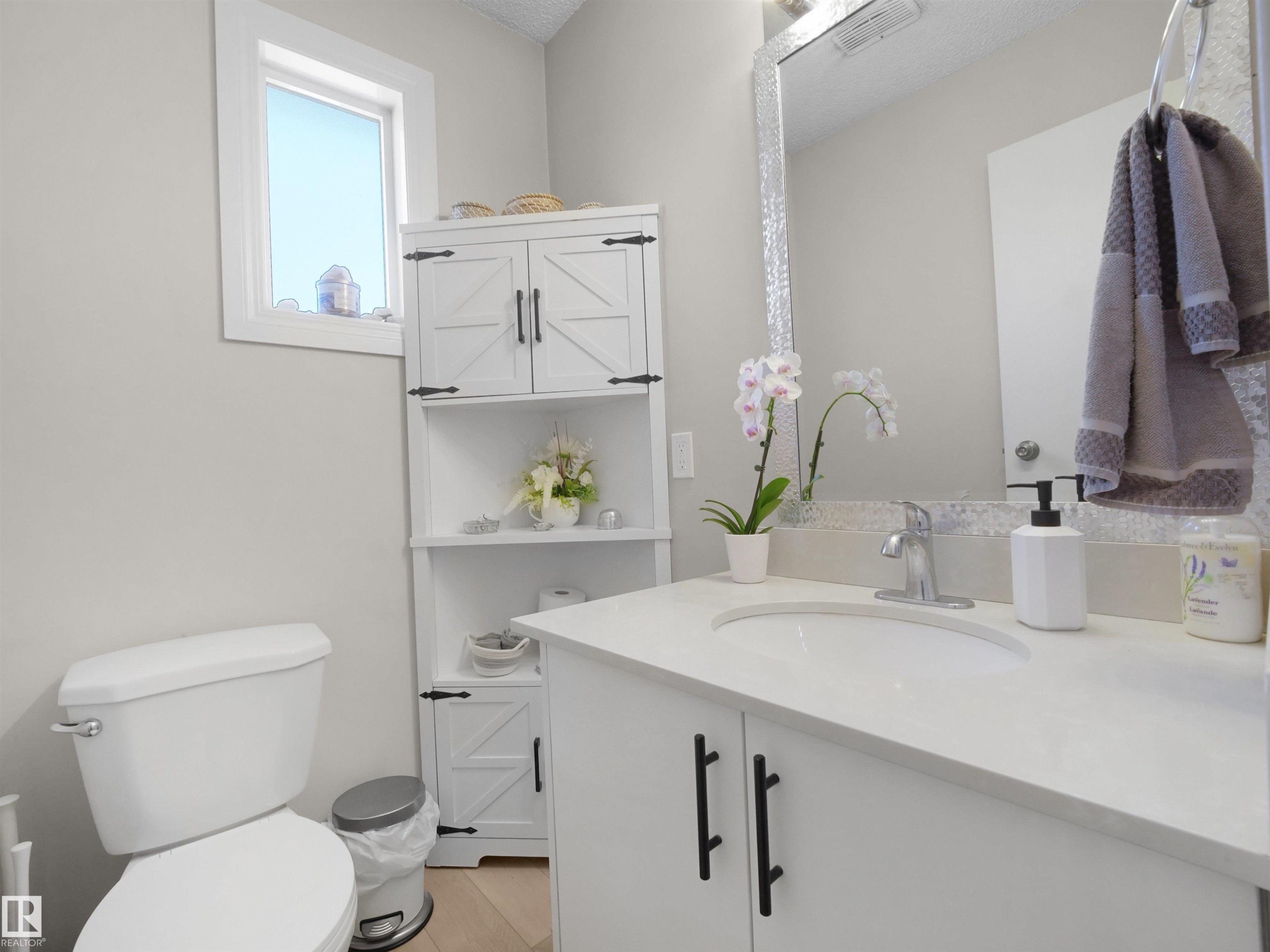 Bathroom featuring a white vanity with integrated sink, chrome faucet, and white countertop - 575 Dunluce Road, Edmonton, AB