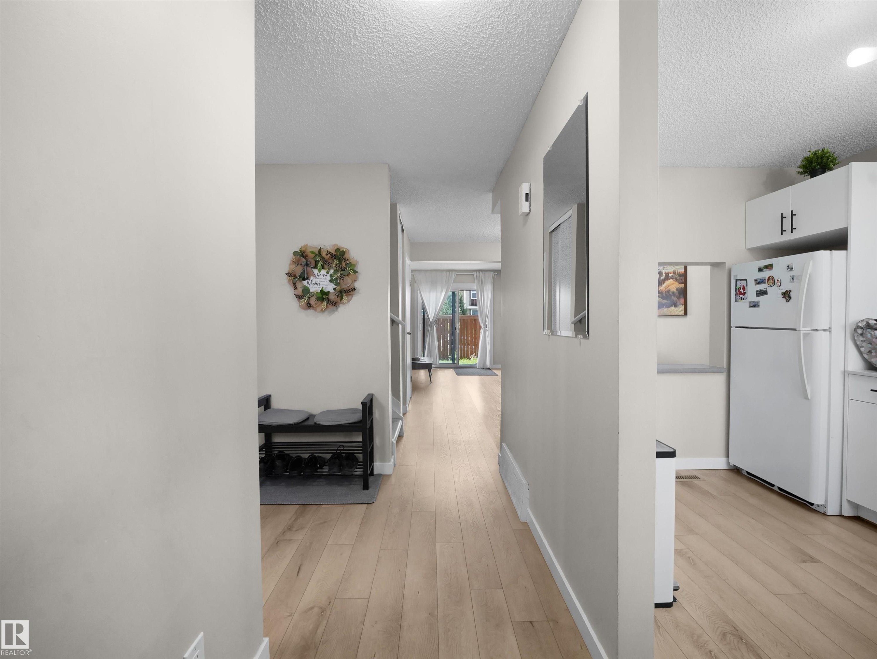 Bright hallway featuring light wood-finish flooring, neutral wall paint, and recessed lighting - 575 Dunluce Road, Edmonton, AB