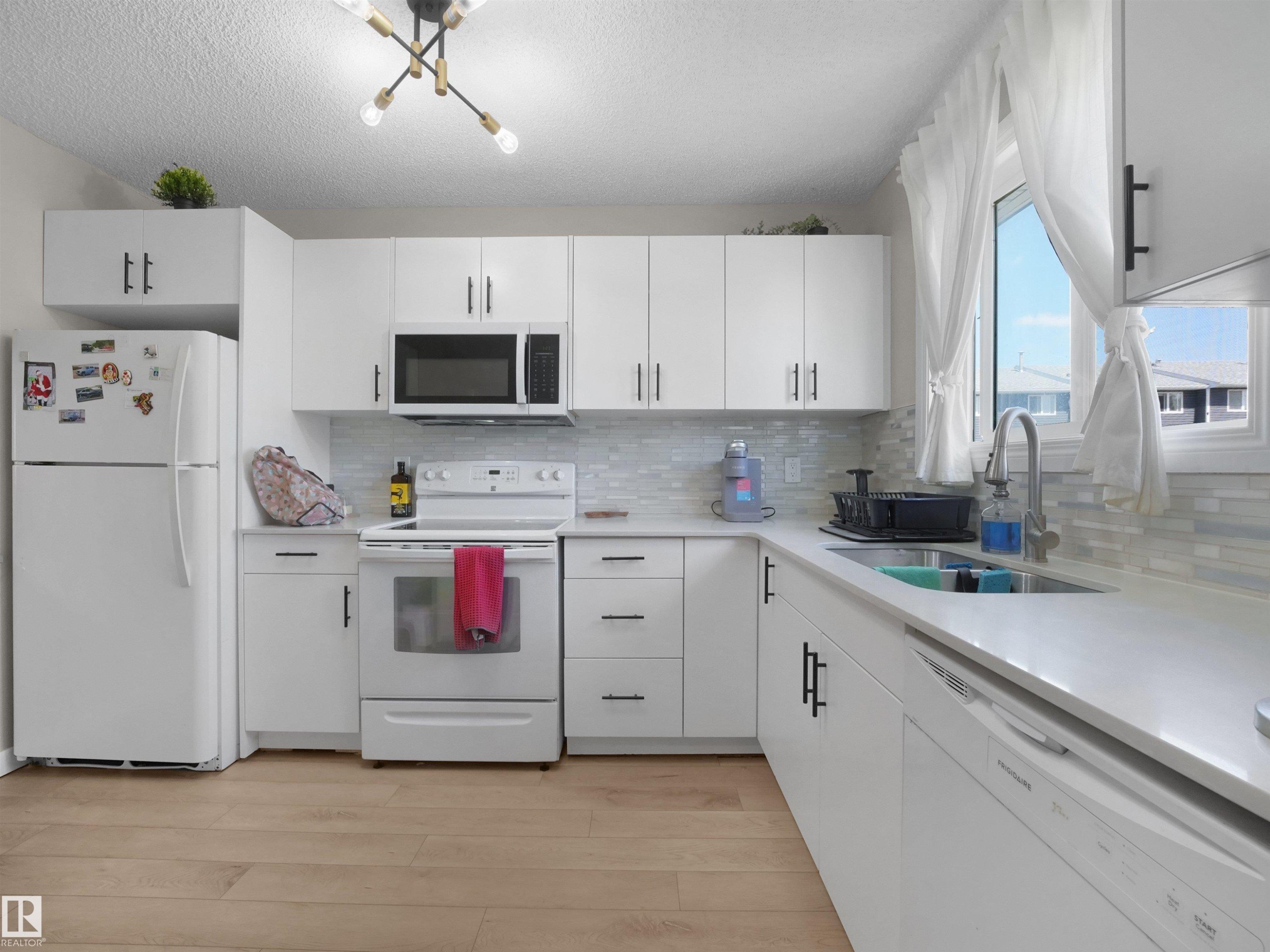 Kitchen featuring white cabinetry, light countertops, and wood-finish flooring - 575 Dunluce Road, Edmonton, AB