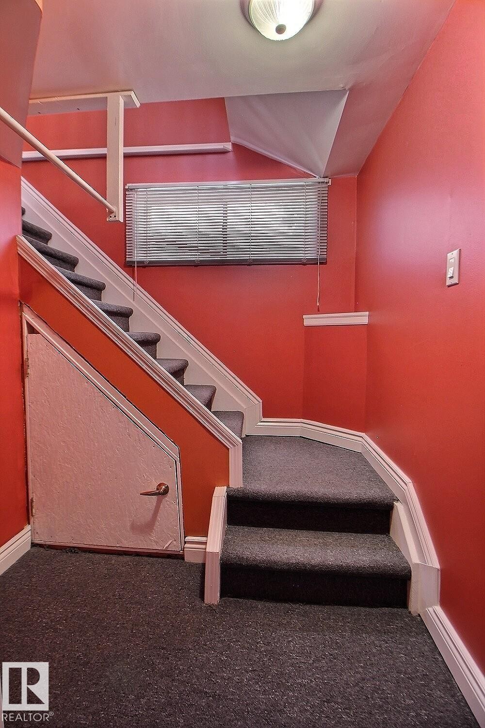 Staircase featuring dark gray carpeted steps and white risers - 11312 127 Street Nw, Edmonton, AB