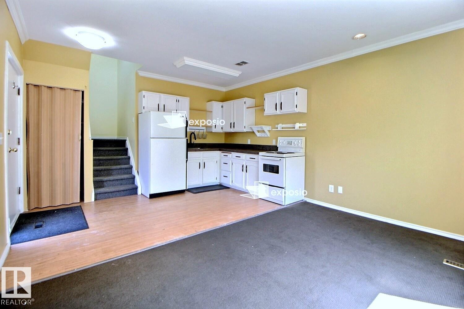 Kitchen area featuring white cabinetry, dark countertops, and white appliances - 11312 127 Street Nw, Edmonton, AB