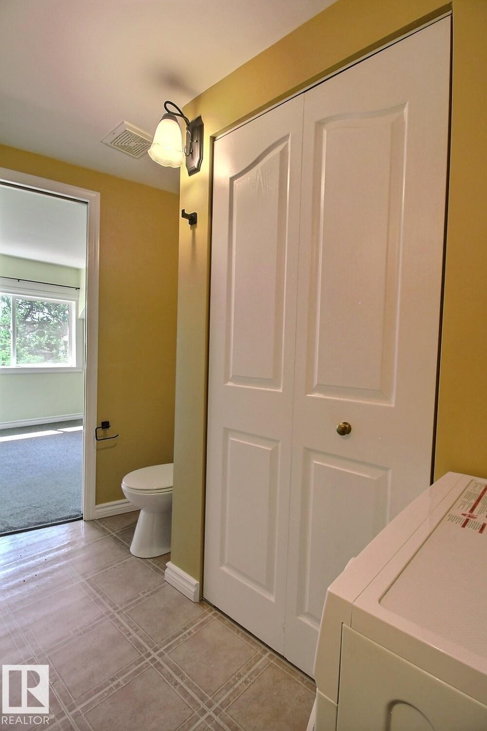 White bi-fold doors, white baseboards, and a wall-mounted light fixture - 11312 127 Street Nw, Edmonton, AB