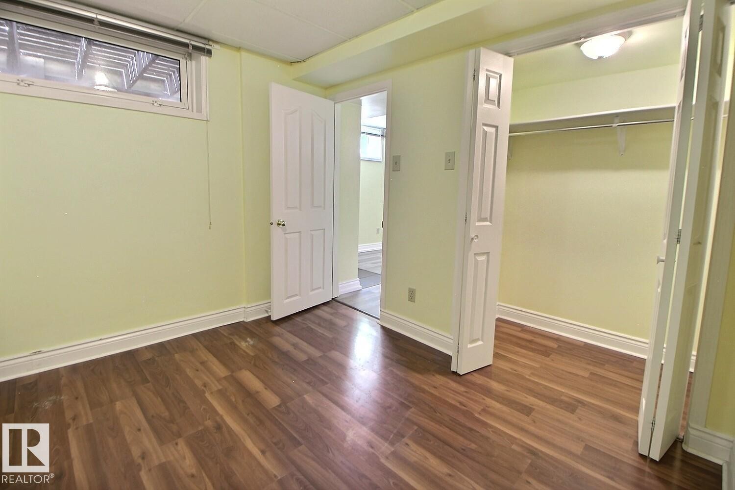 Room featuring wood-finish flooring, light-toned walls, and white trim - 11312 127 Street Nw, Edmonton, AB