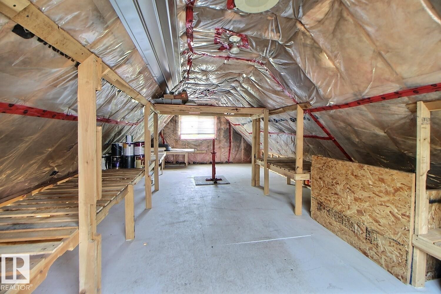 Attic space featuring exposed insulation, concrete flooring, and built-in wooden shelving - 11312 127 Street Nw, Edmonton, AB