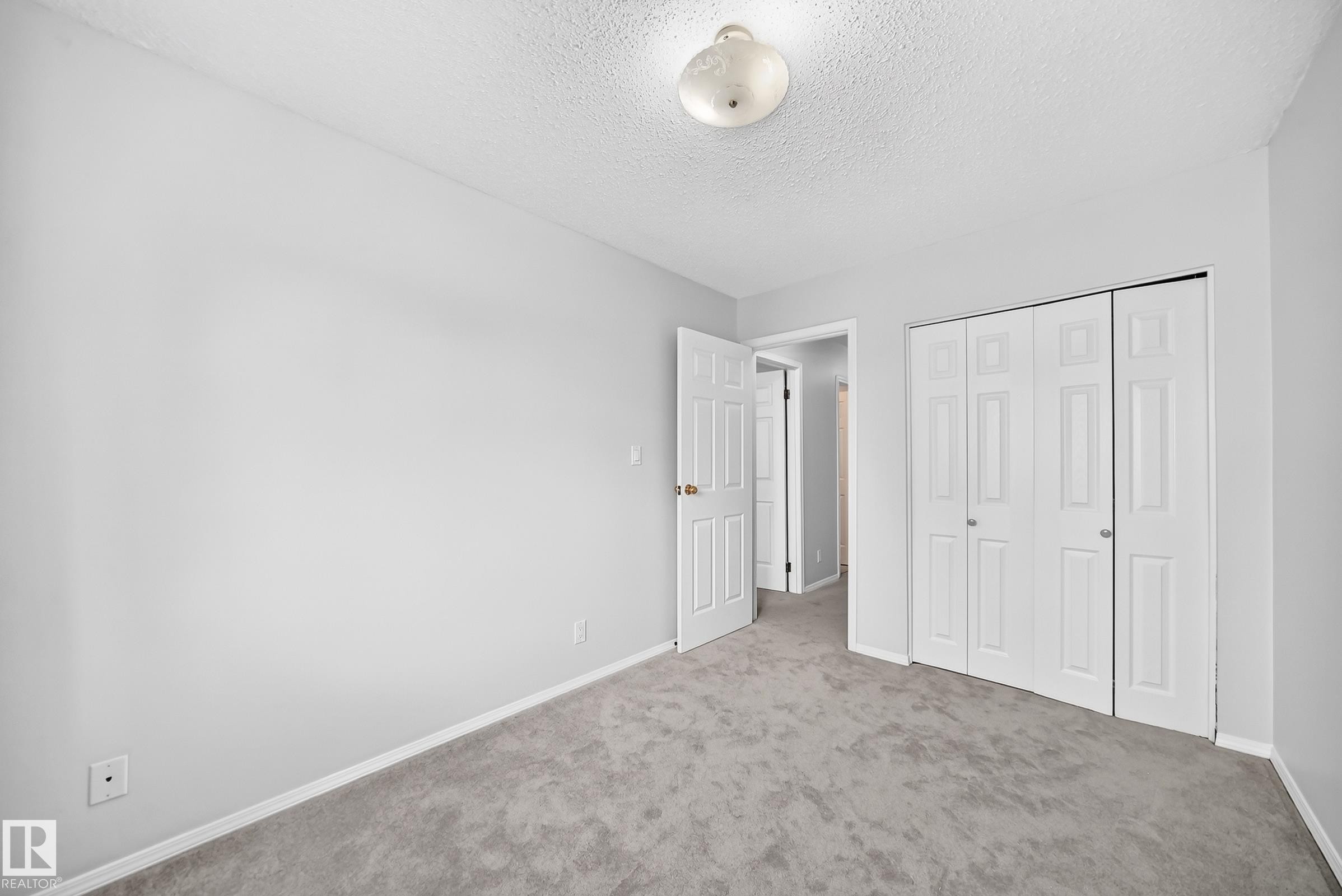Carpeted room featuring light gray walls, white trim, and a white ceiling with a flush-mount light fixture - 11447 22 Avenue Nw, Edmonton, AB - Indoor