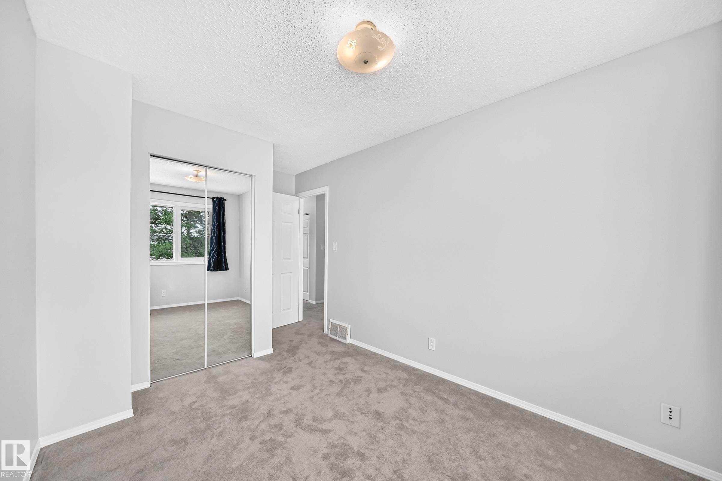Carpeted interior space featuring light gray walls and white baseboards - 11447 22 Avenue Nw, Edmonton, AB - Indoor Photo Showing Other Room