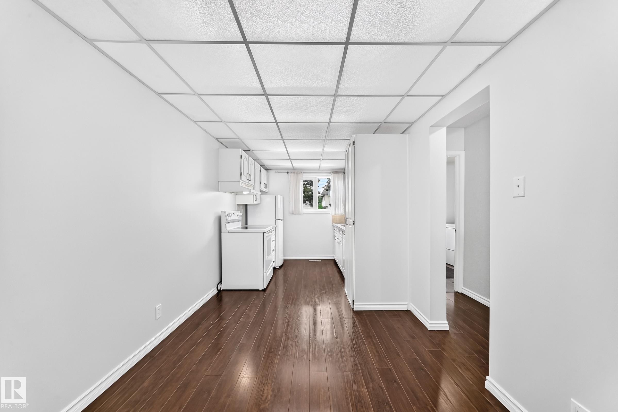 Galley kitchen featuring wood-finish flooring, white cabinetry, a window with natural light, and white appliances - 11447 22 Avenue Nw, Edmonton, AB - Indoor Photo Showing Other Room