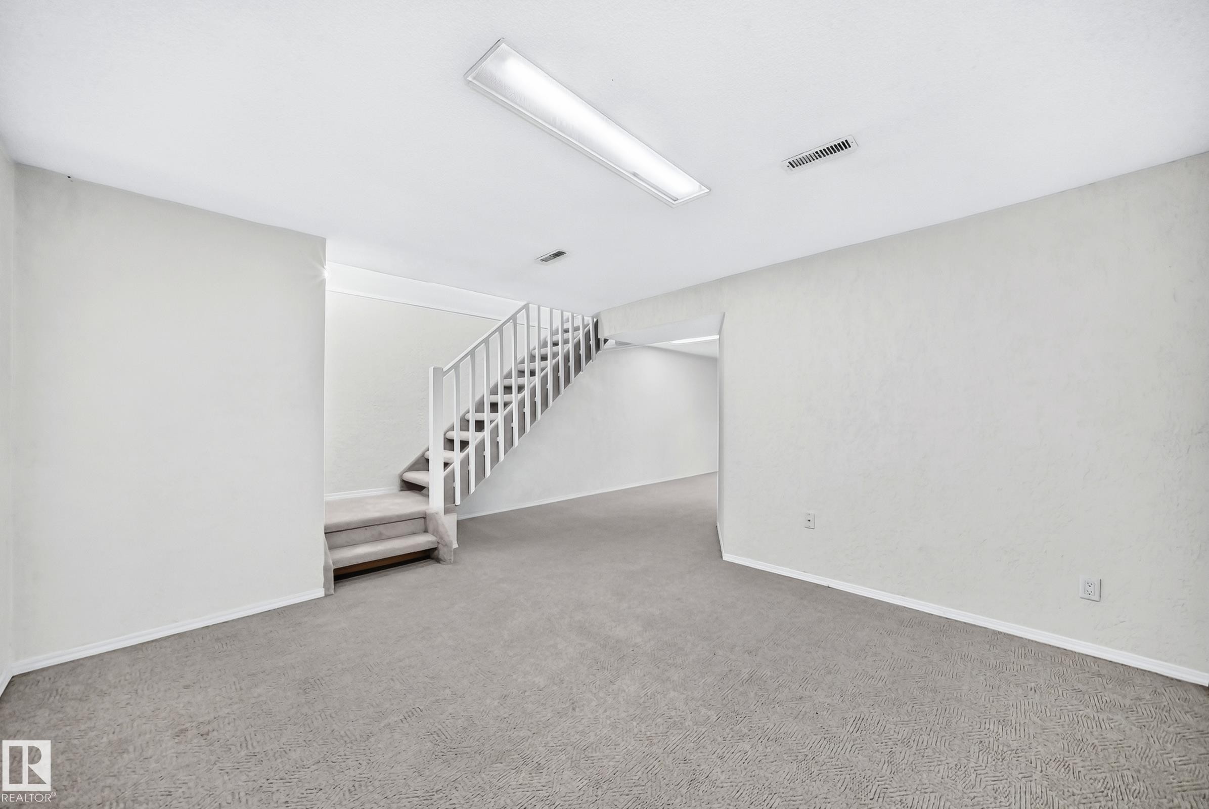 Carpeted room featuring a staircase with white railing, recessed lighting, and white baseboards - 11447 22 Avenue Nw, Edmonton, AB - Indoor Photo Showing Other Room