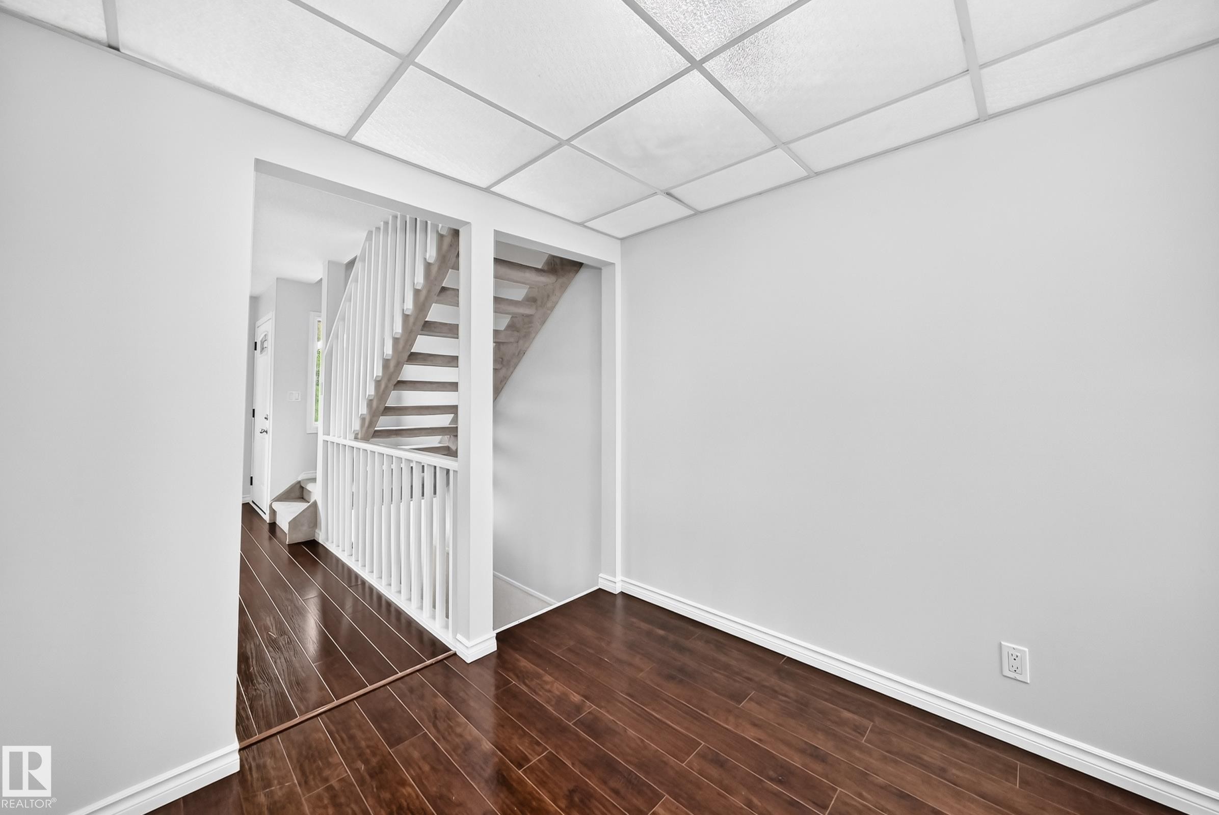Interior space featuring dark wood-finish flooring, white baseboards, and light gray walls - 11447 22 Avenue Nw, Edmonton, AB - Indoor Photo Showing Other Room