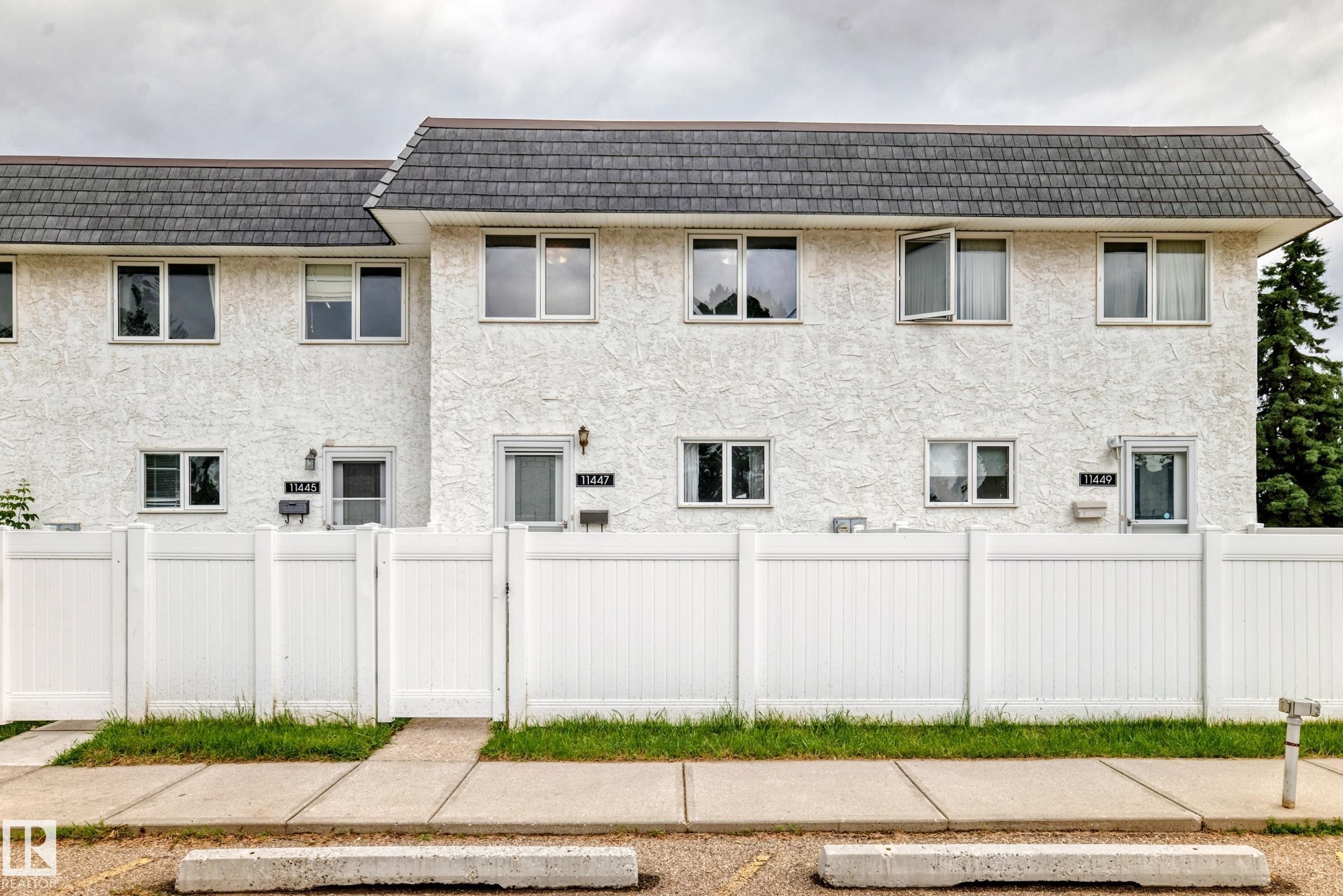 Multi-unit building featuring white textured stucco exterior and a dark shingle roof - 11447 22 Avenue Nw, Edmonton, AB - Outdoor