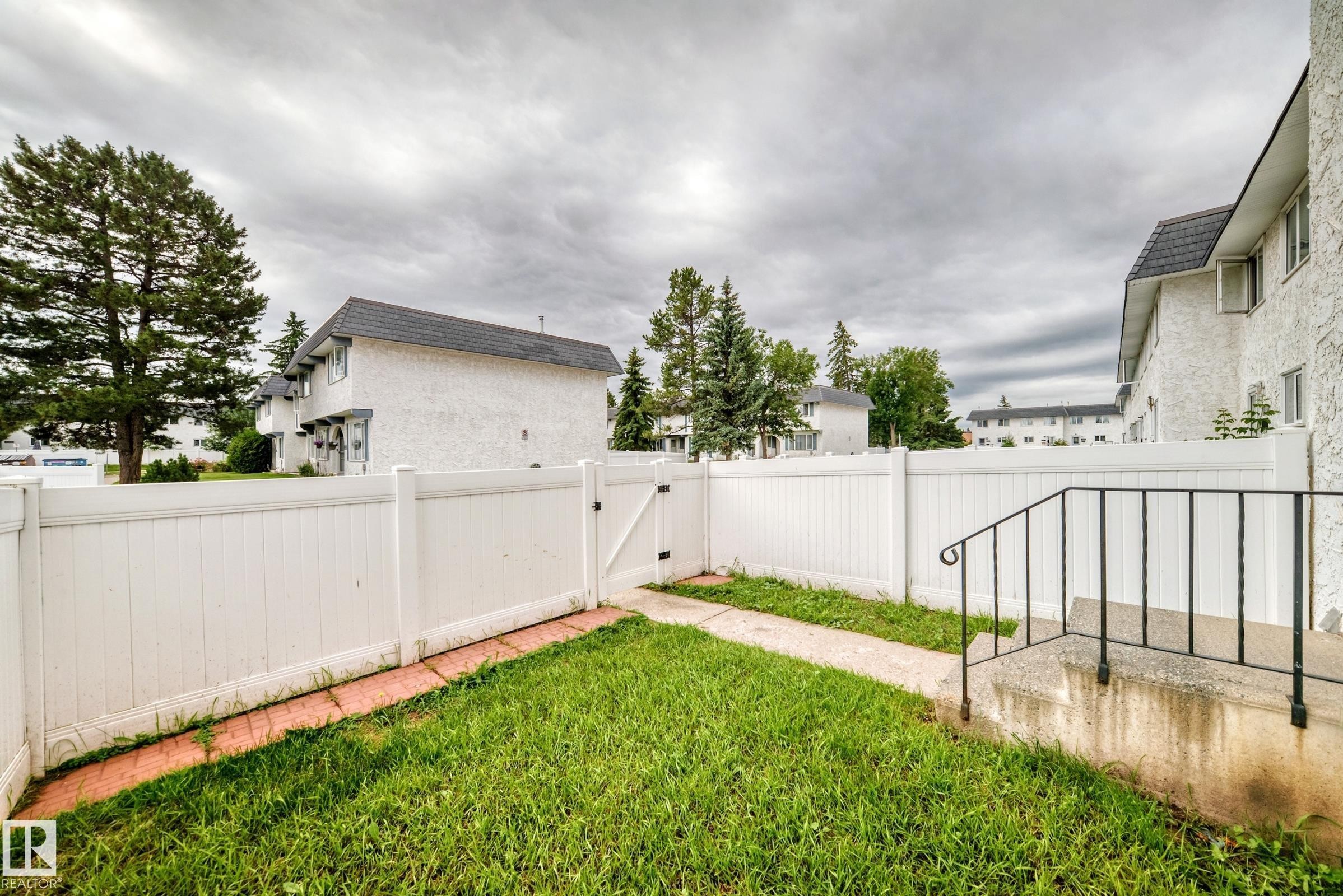 Private outdoor space featuring a white privacy fence and a small lawn area - 11447 22 Avenue Nw, Edmonton, AB - Outdoor