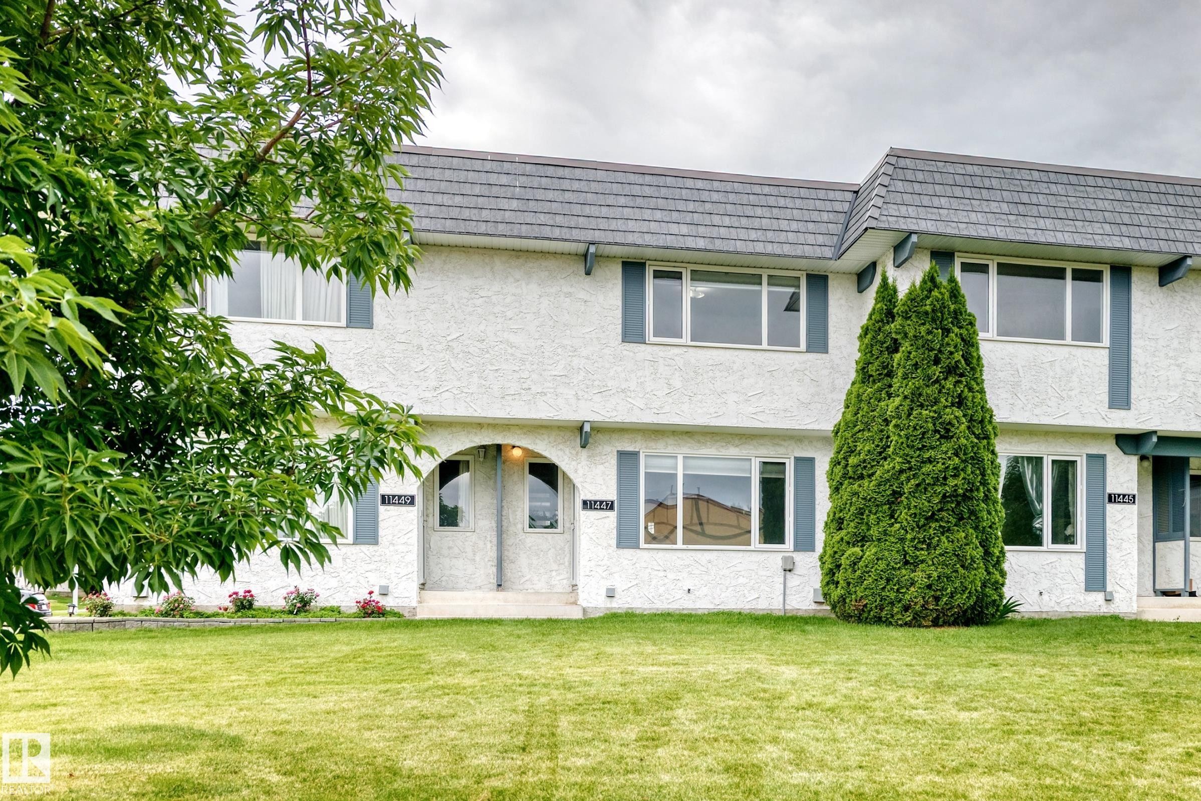 Two-story townhome with textured white stucco exterior and dark gray shingle roof - 11447 22 Avenue Nw, Edmonton, AB - Outdoor