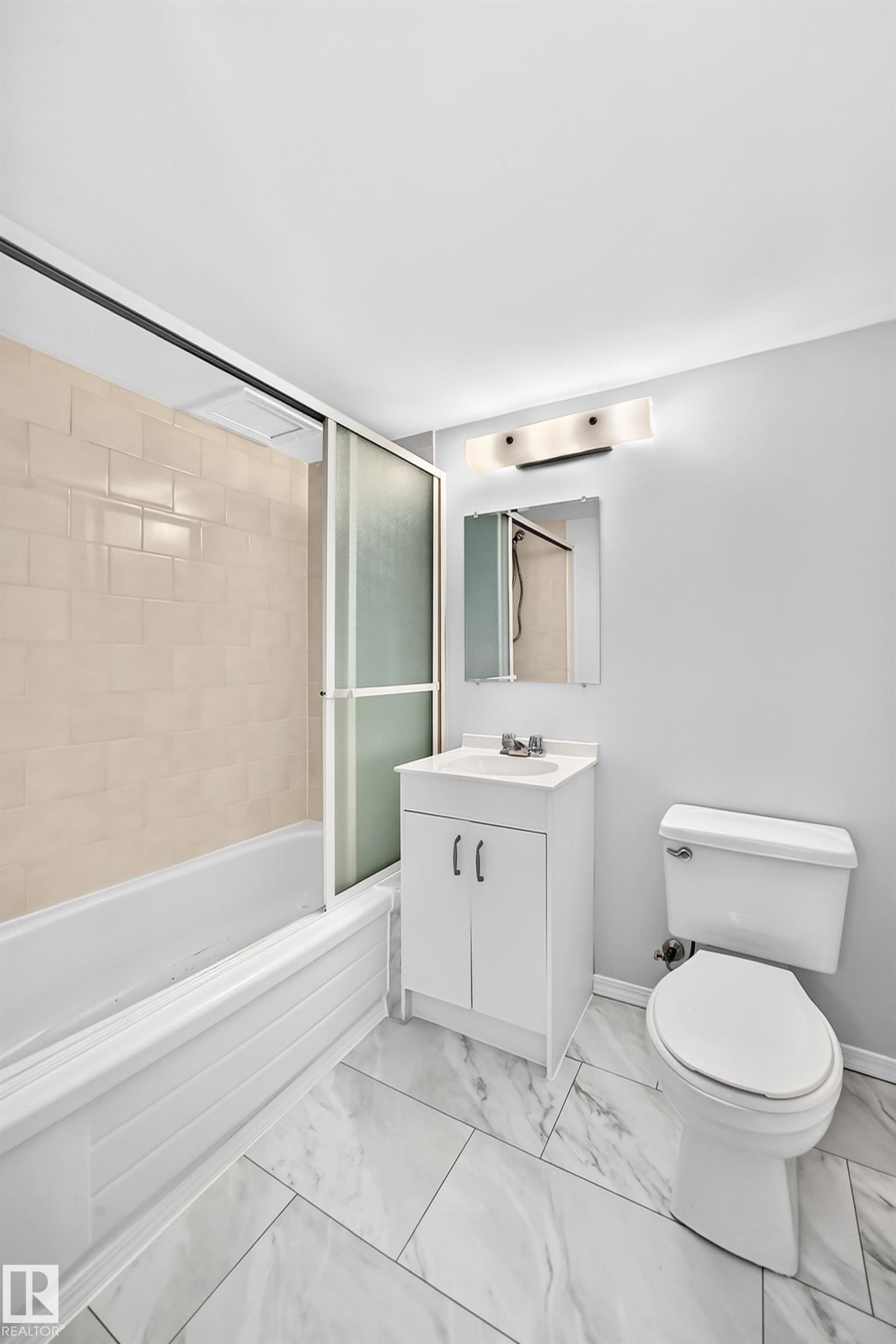 Light-toned porcelain tile flooring complements the white vanity with integrated sink - 11447 22 Avenue Nw, Edmonton, AB - Indoor Photo Showing Bathroom