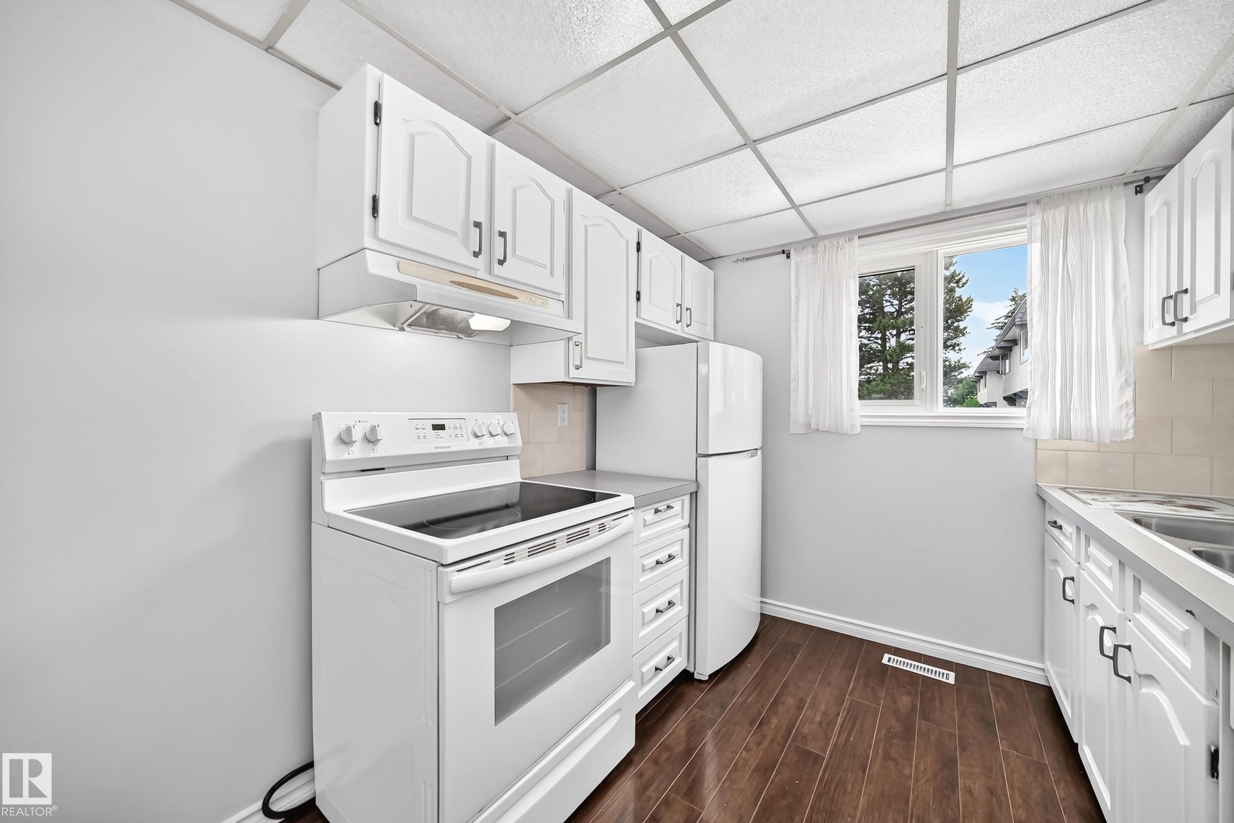 Kitchen featuring white cabinetry, dark wood-finish flooring, and white appliances - 11447 22 Avenue Nw, Edmonton, AB - Indoor Photo Showing Kitchen