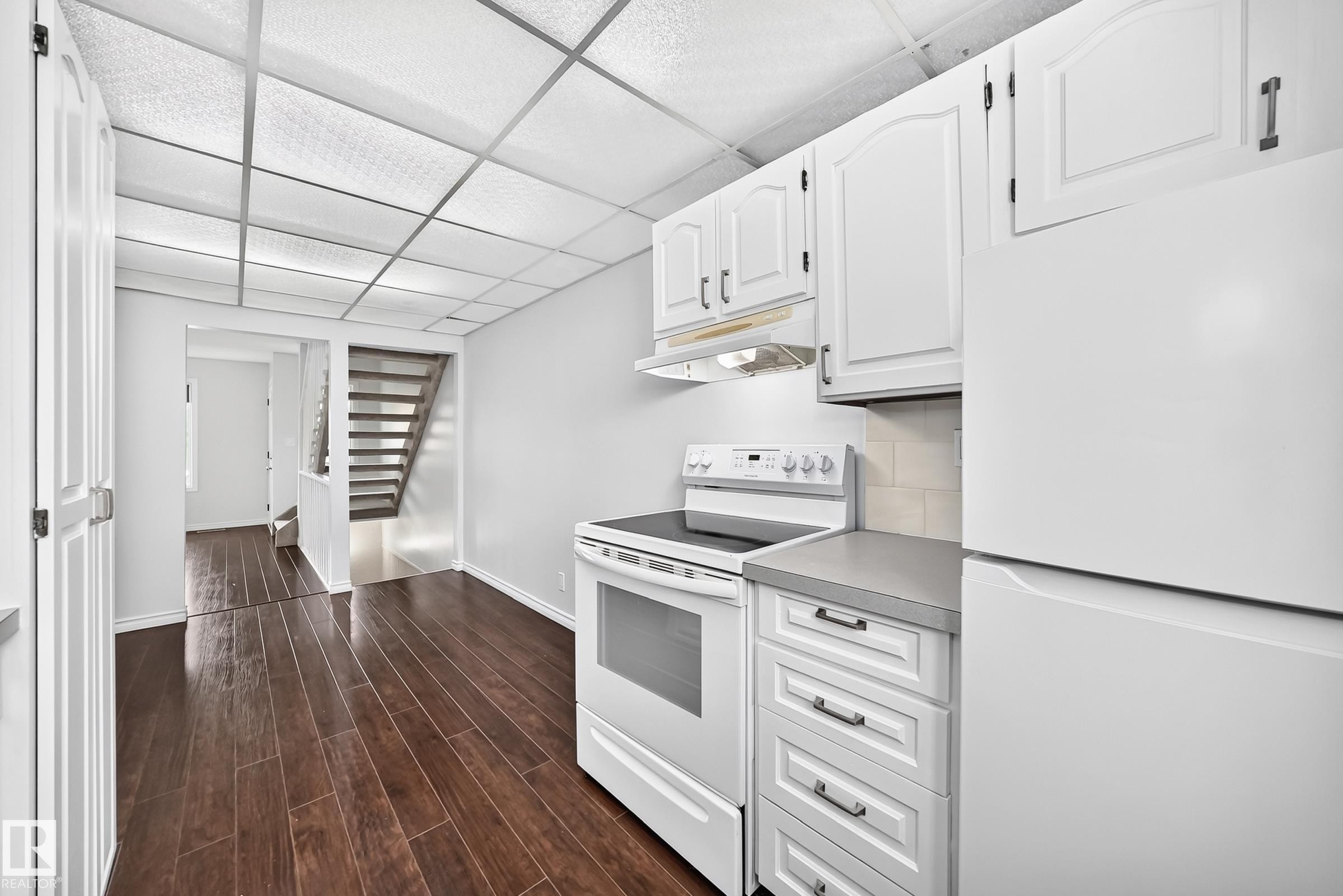 Contemporary kitchen featuring white cabinetry, a built-in range with overhead ventilation, and a white refrigerator - 11447 22 Avenue Nw, Edmonton, AB - Indoor Photo Showing Kitchen