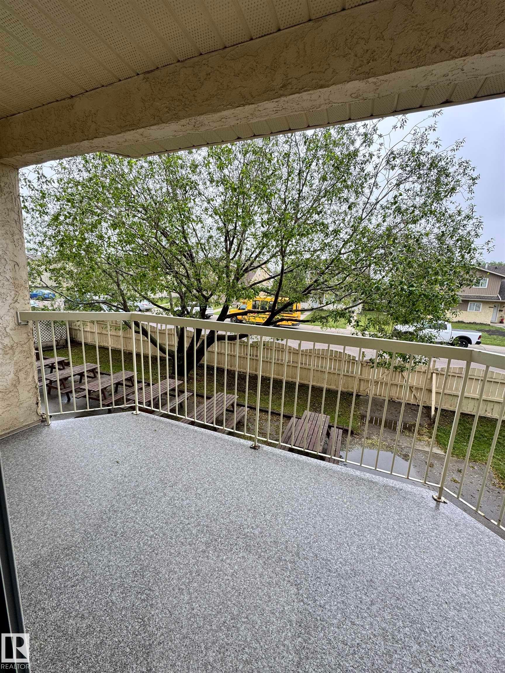 Balcony featuring a speckled gray surface, light-colored railing, and a textured ceiling - 207 18012 95 Avenue, Edmonton, AB