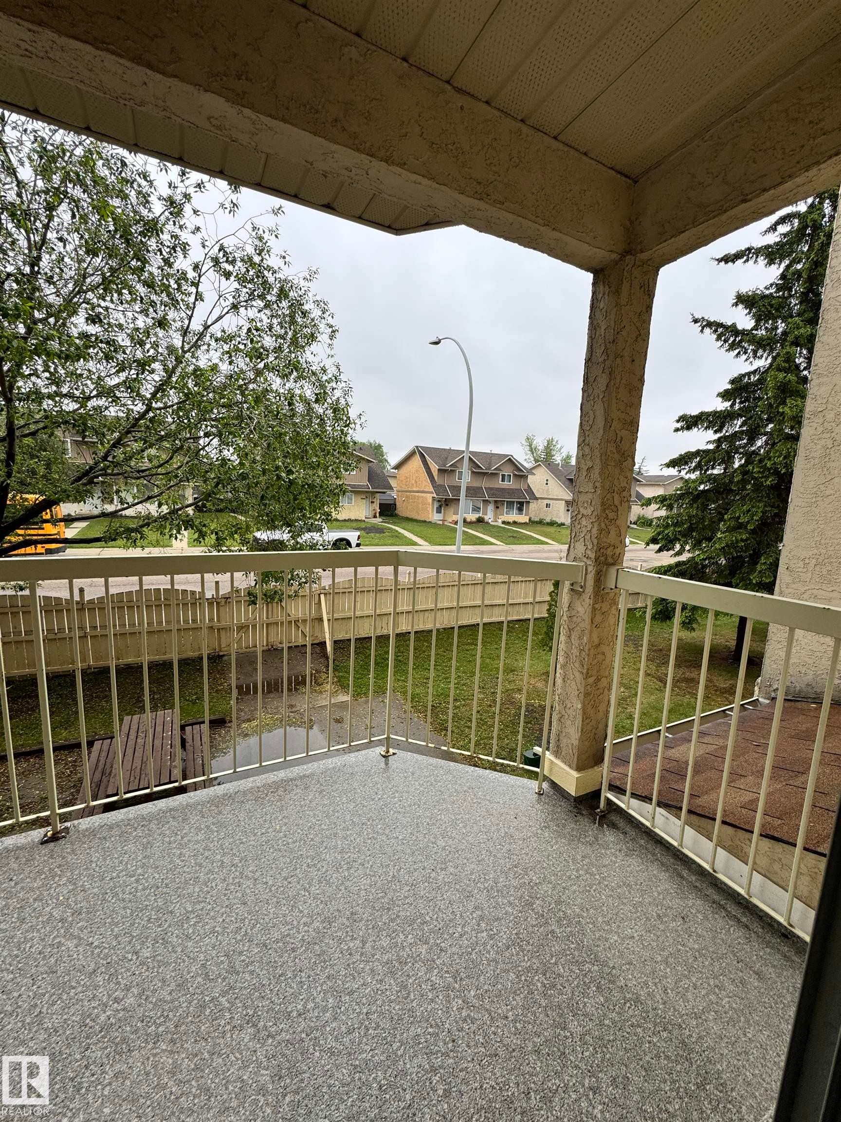 Exterior balcony featuring textured stucco walls, a durable speckled surface, and metal railings - 207 18012 95 Avenue, Edmonton, AB