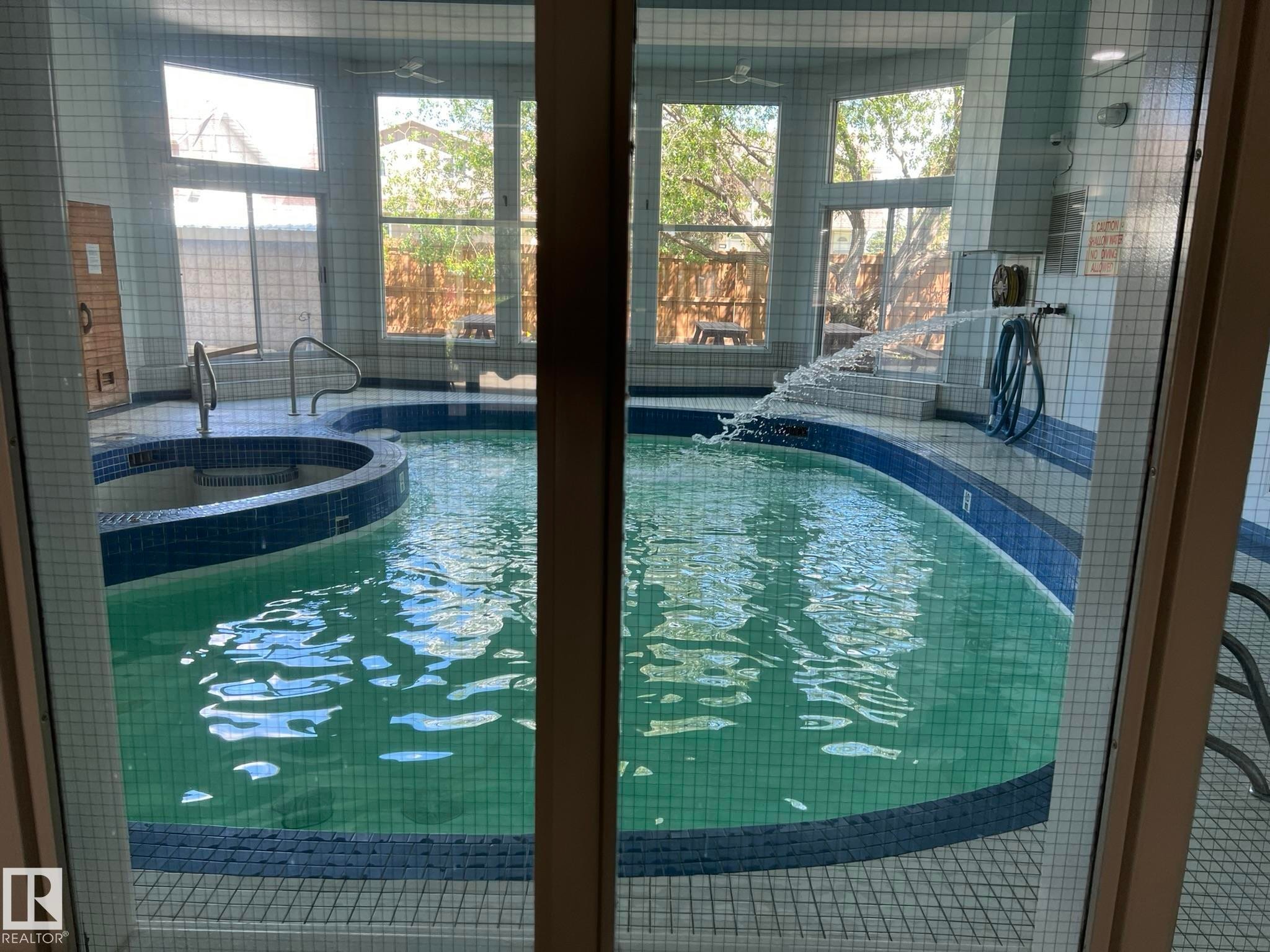 Indoor aquatic area featuring a curved-edge pool and integrated spa - 207 18012 95 Avenue, Edmonton, AB