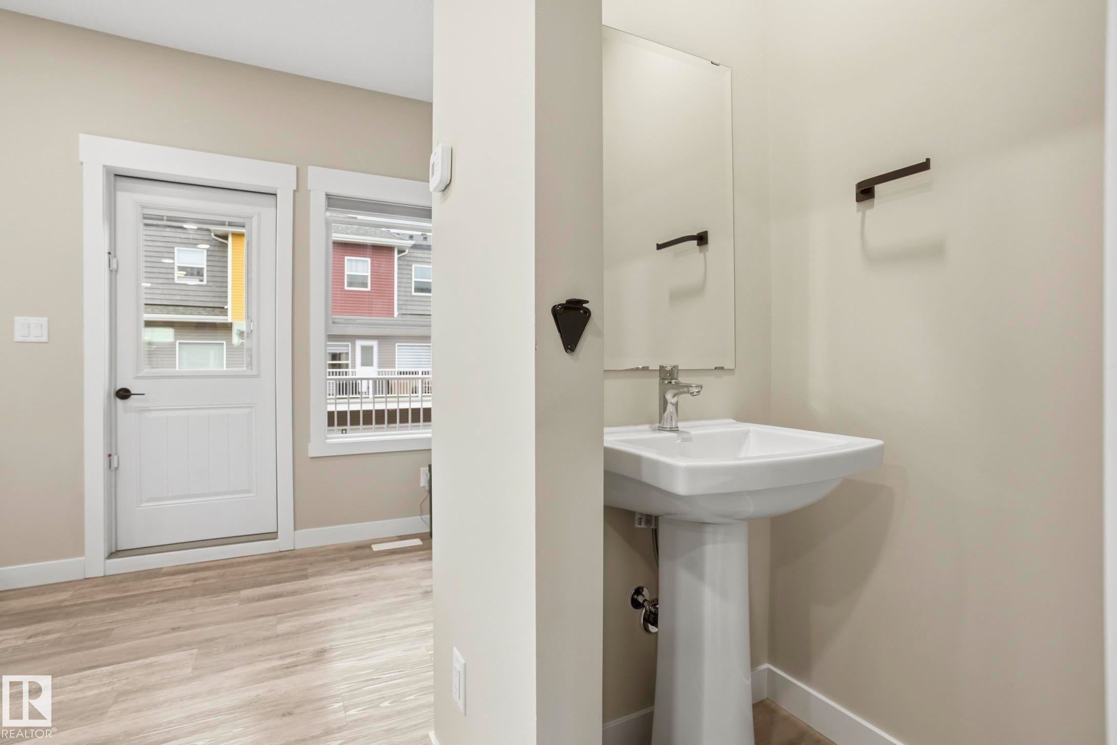 Pedestal sink with chrome faucet, complemented by a frameless mirror and matte black hardware - 36 150 Everitt Dr, St. Albert, AB - Indoor Photo Showing Bathroom