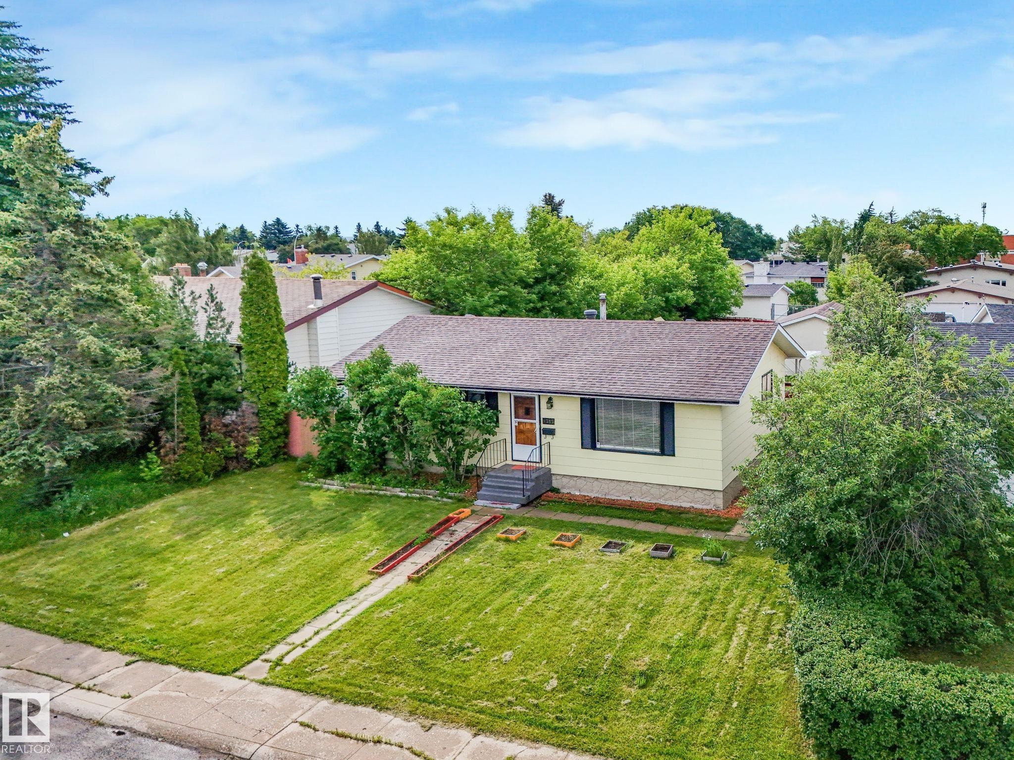 Ranch-style residence featuring a brown shingle roof and light yellow siding - 9315 151 Avenue, Edmonton, AB