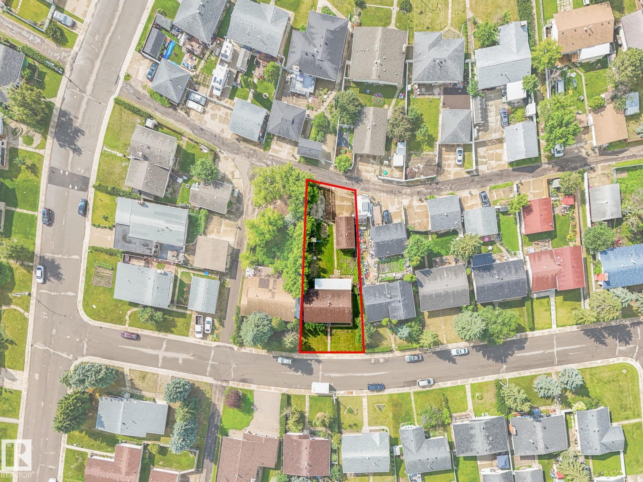 Aerial view showcasing the property outlined in red, featuring a rectangular lot with a primary residence and a detached structure - 9315 151 Avenue, Edmonton, AB