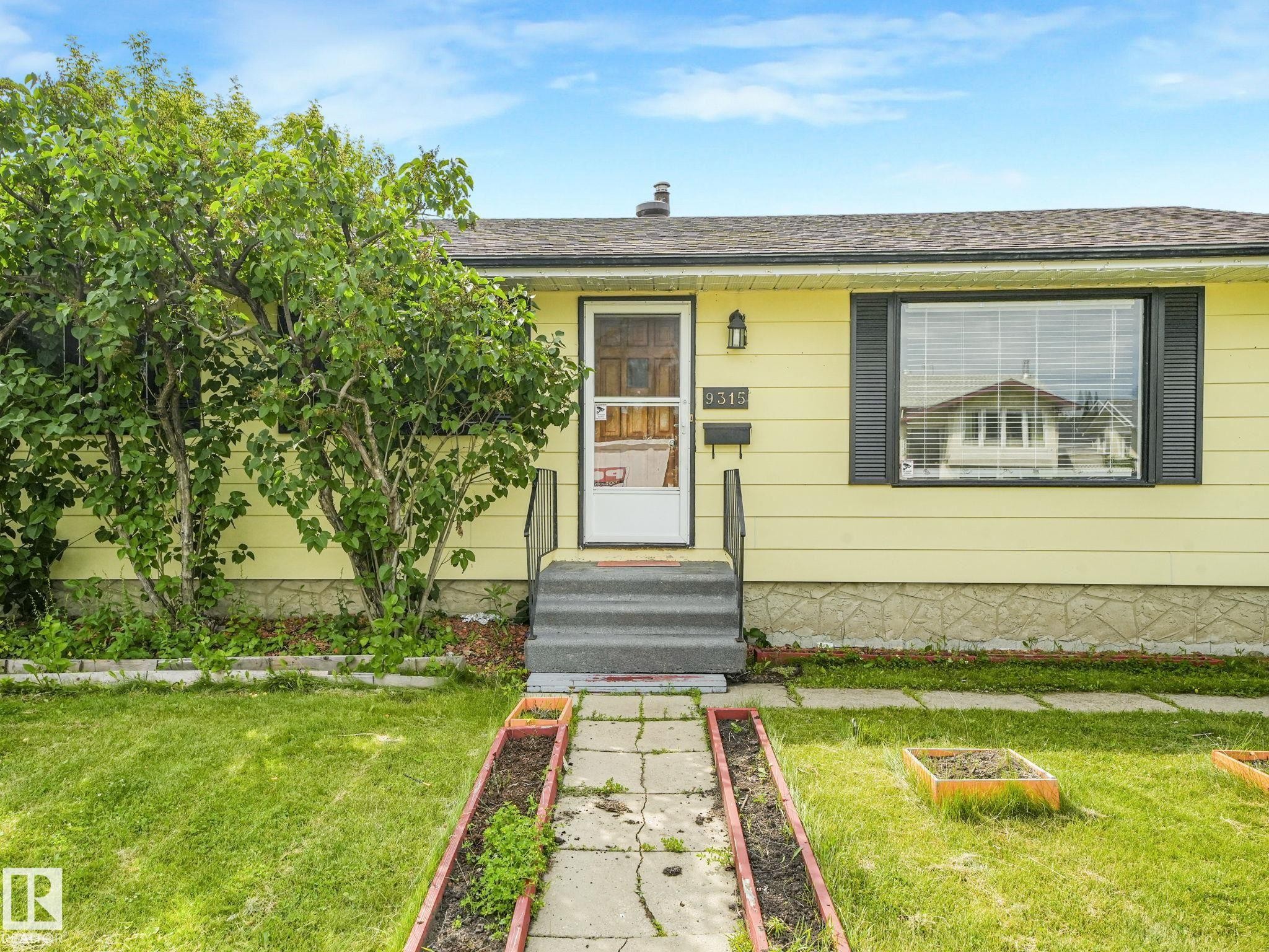 Exterior facade featuring yellow siding and black window shutters - 9315 151 Avenue, Edmonton, AB