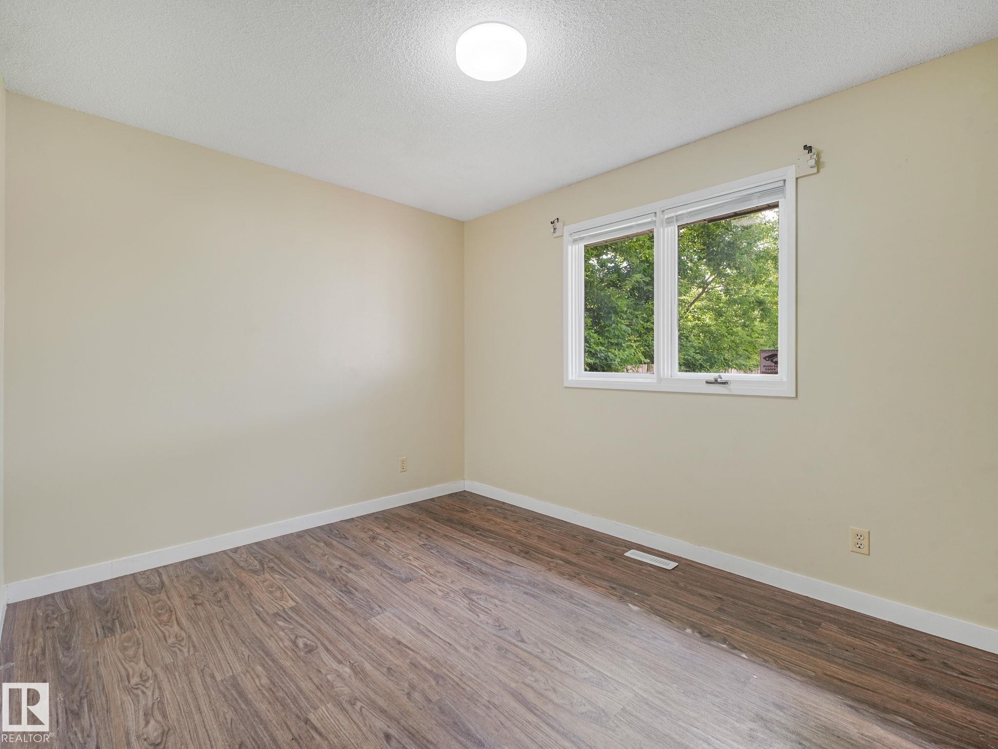 Interior room with wood-finish flooring, light neutral walls, and white trim - 9315 151 Avenue, Edmonton, AB
