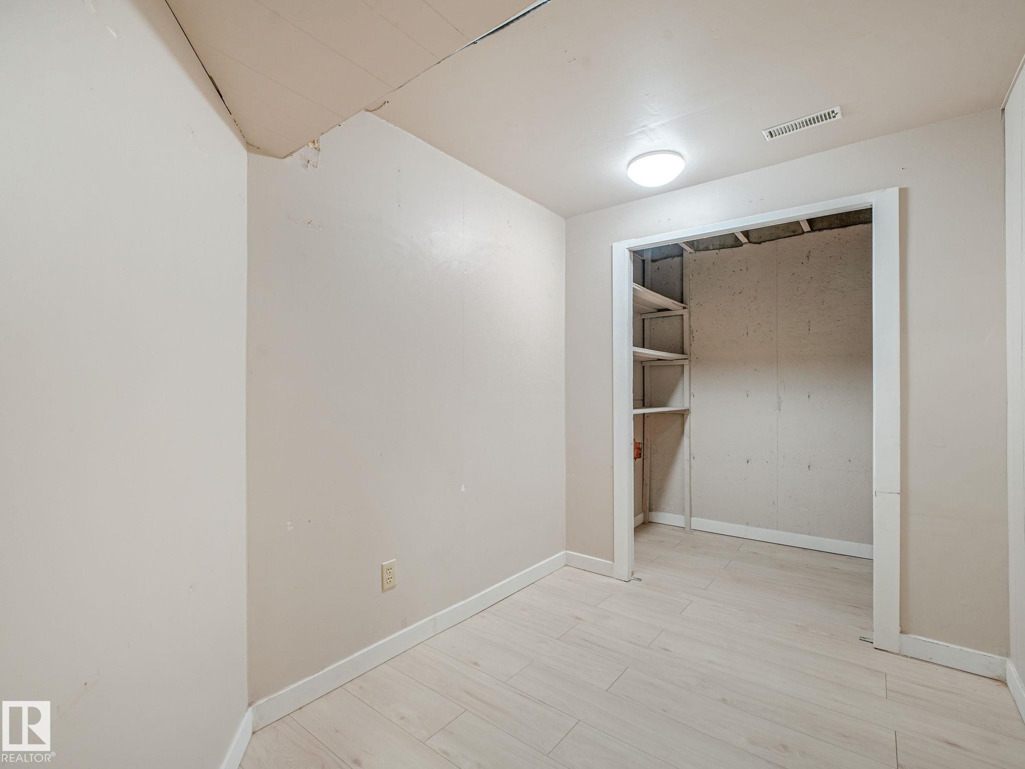 Room featuring light-toned walls, wood-finish flooring, and a flush-mount ceiling light - 9315 151 Avenue, Edmonton, AB
