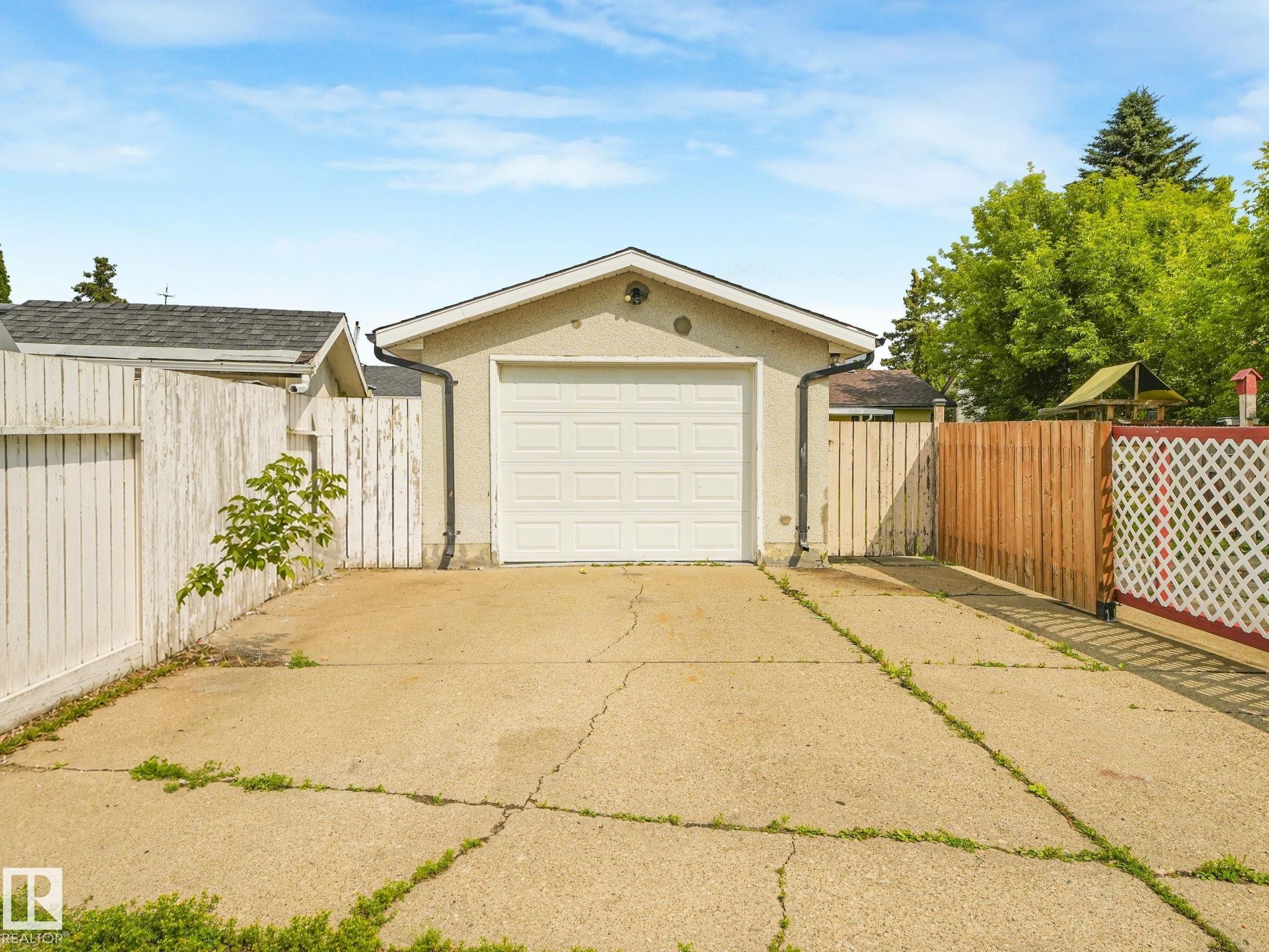Detached single-car garage with a panel door, stucco exterior, and concrete driveway - 9315 151 Avenue, Edmonton, AB