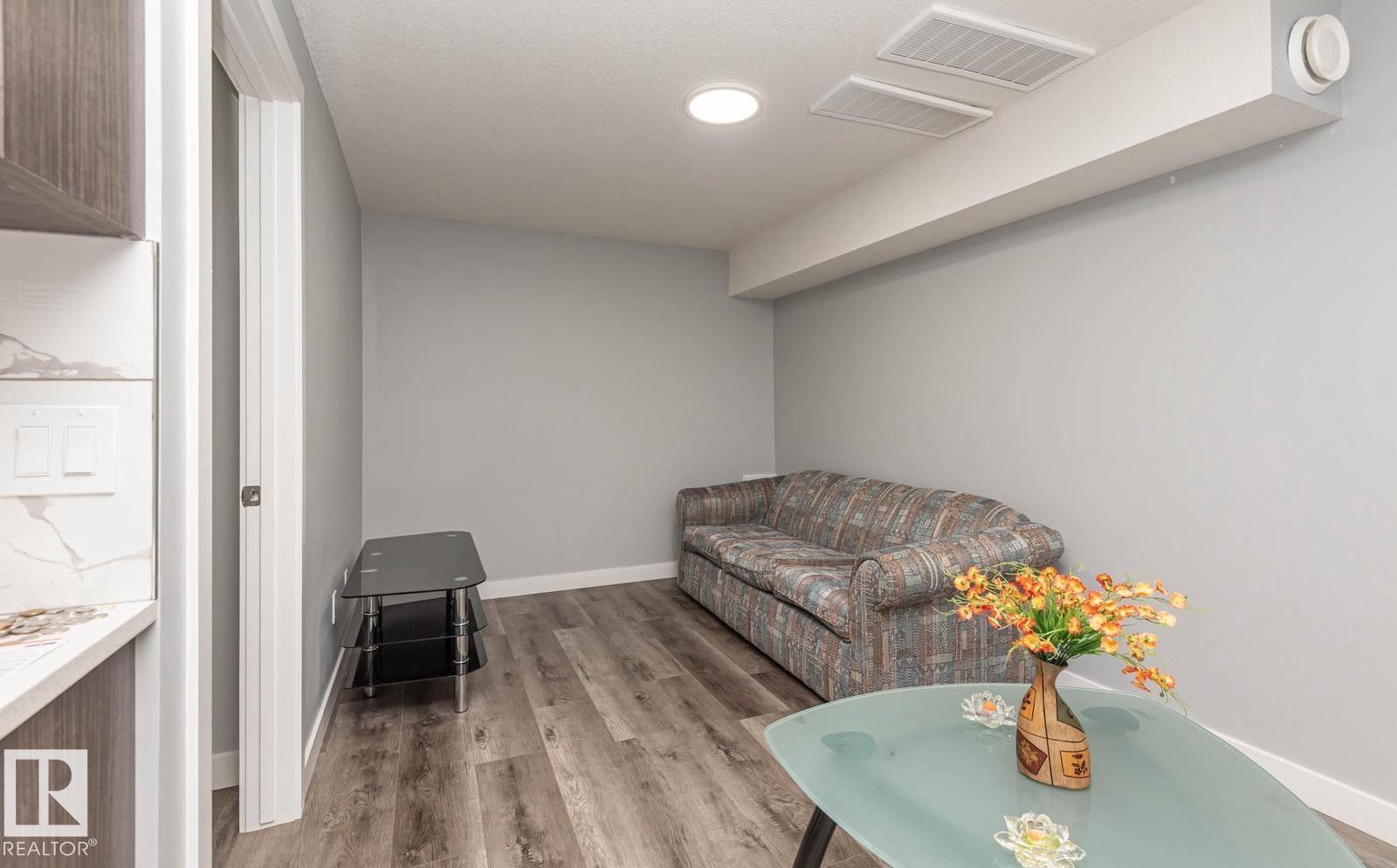 Open-concept living space featuring wood-finish flooring, recessed lighting, and light grey wall tones - 2635 Donaghey Crescent, Edmonton, AB