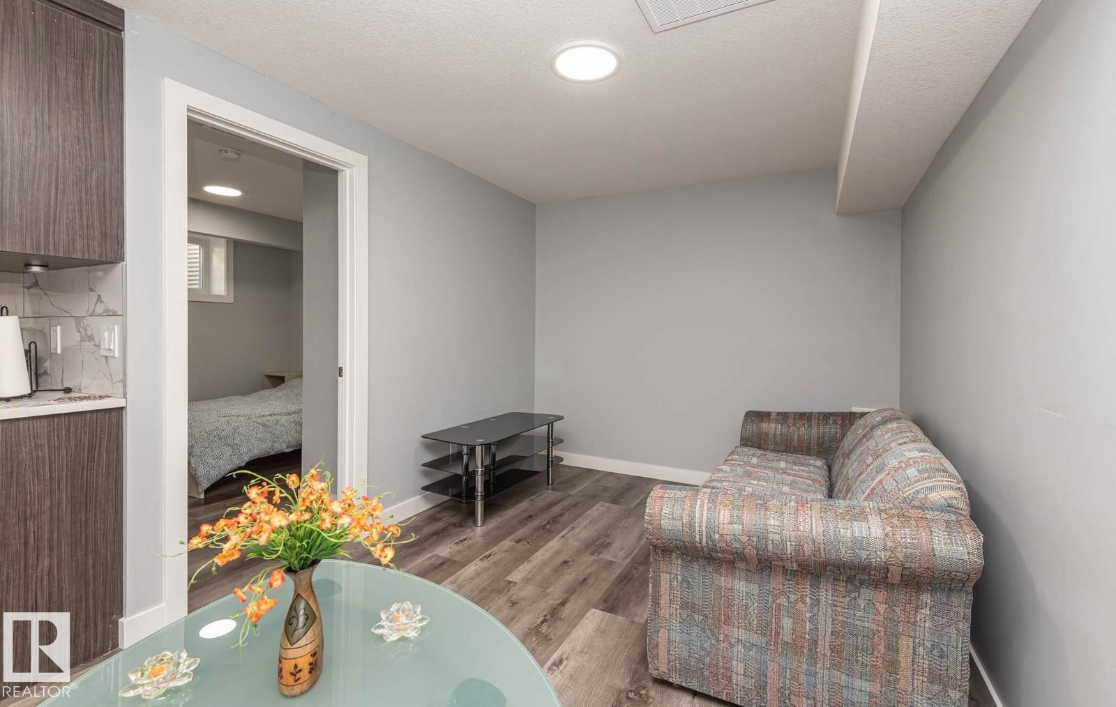 Finished lower level featuring recessed lighting, wood-finish flooring, light gray wall paint, and a built-in cabinetry area with a white countertop and marble-look backsplash - 2635 Donaghey Crescent, Edmonton, AB