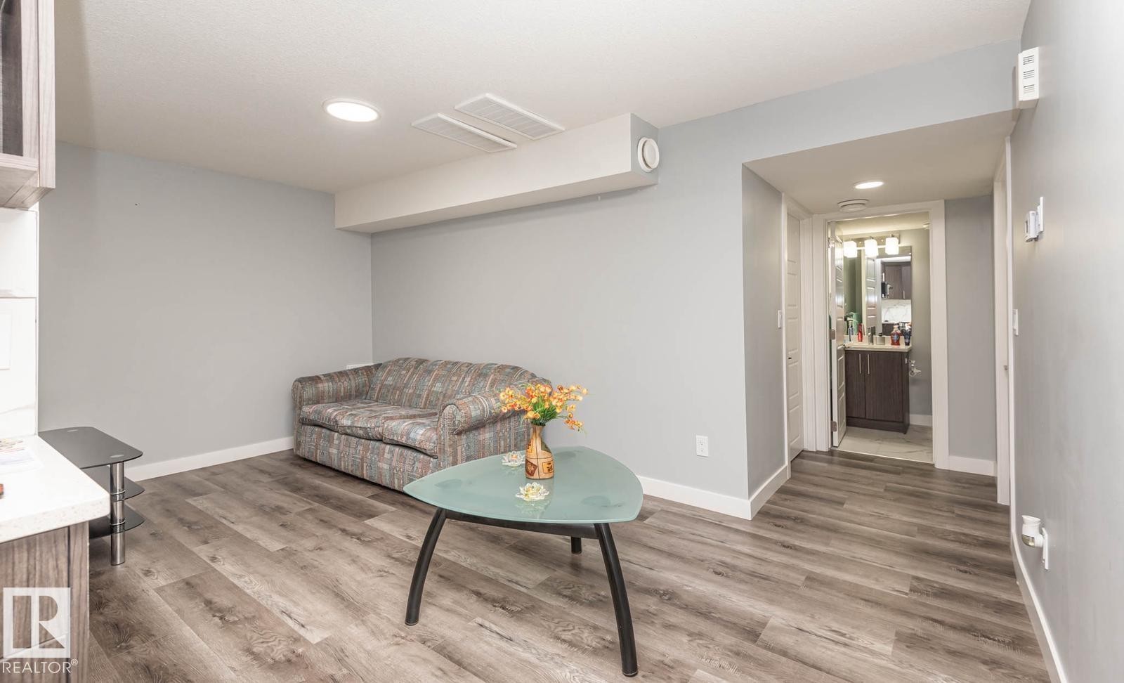 Versatile living area featuring wood-finish flooring, light gray walls, white trim, and recessed lighting - 2635 Donaghey Crescent, Edmonton, AB