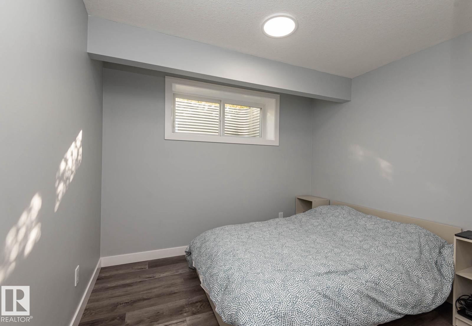 Room featuring wood-finish flooring, recessed lighting, and a white-framed window with blinds - 2635 Donaghey Crescent, Edmonton, AB