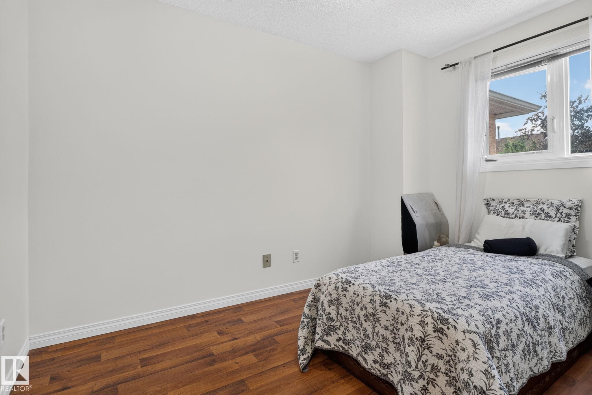 Bright room featuring wood-finish flooring, white baseboards, and a white ceiling - 9503 180A Street Nw, Edmonton, AB - Indoor Photo Showing Bedroom