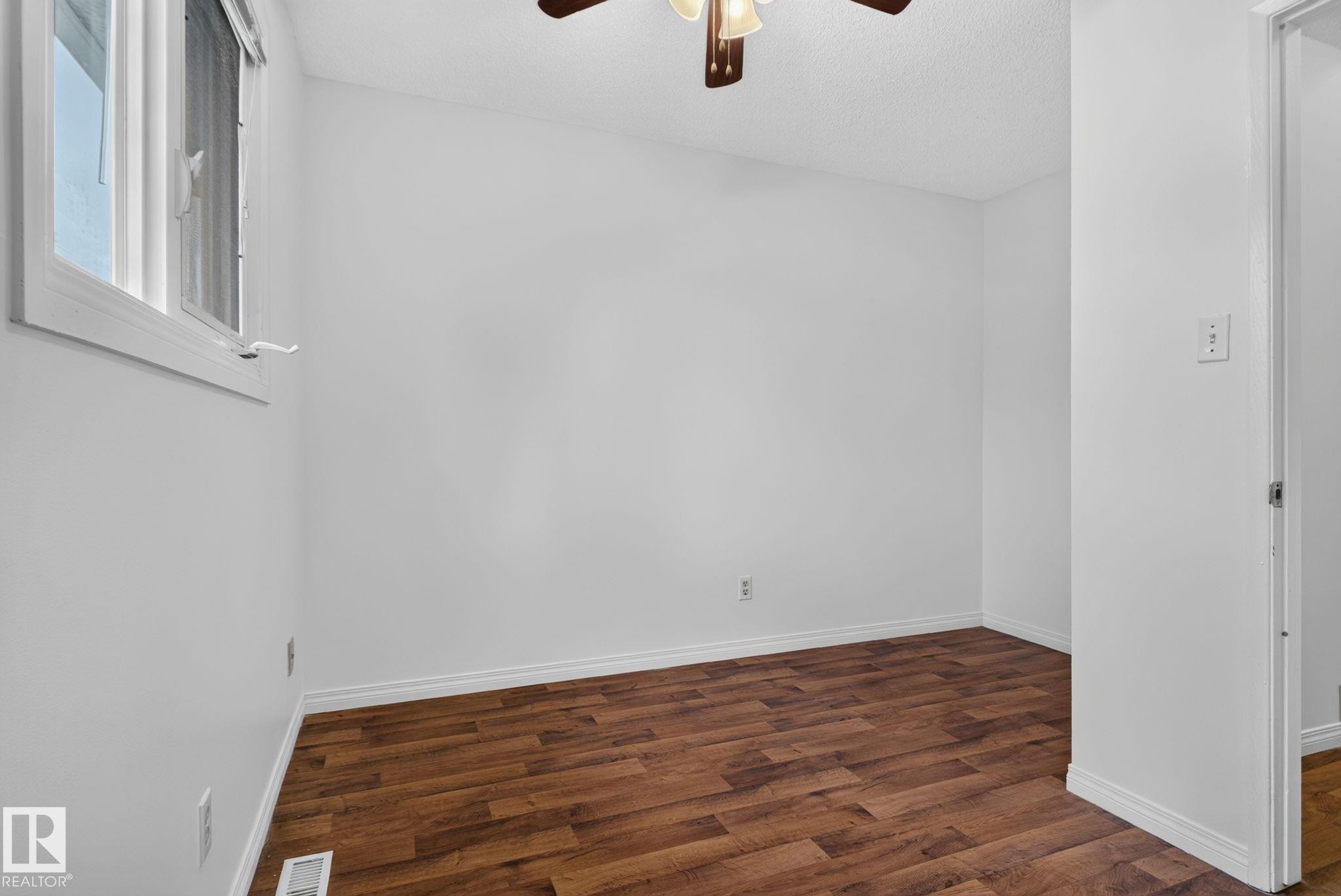 Room featuring wood-finish flooring, white baseboards, and a ceiling fan with integrated lighting - 9503 180A Street Nw, Edmonton, AB - Indoor Photo Showing Other Room