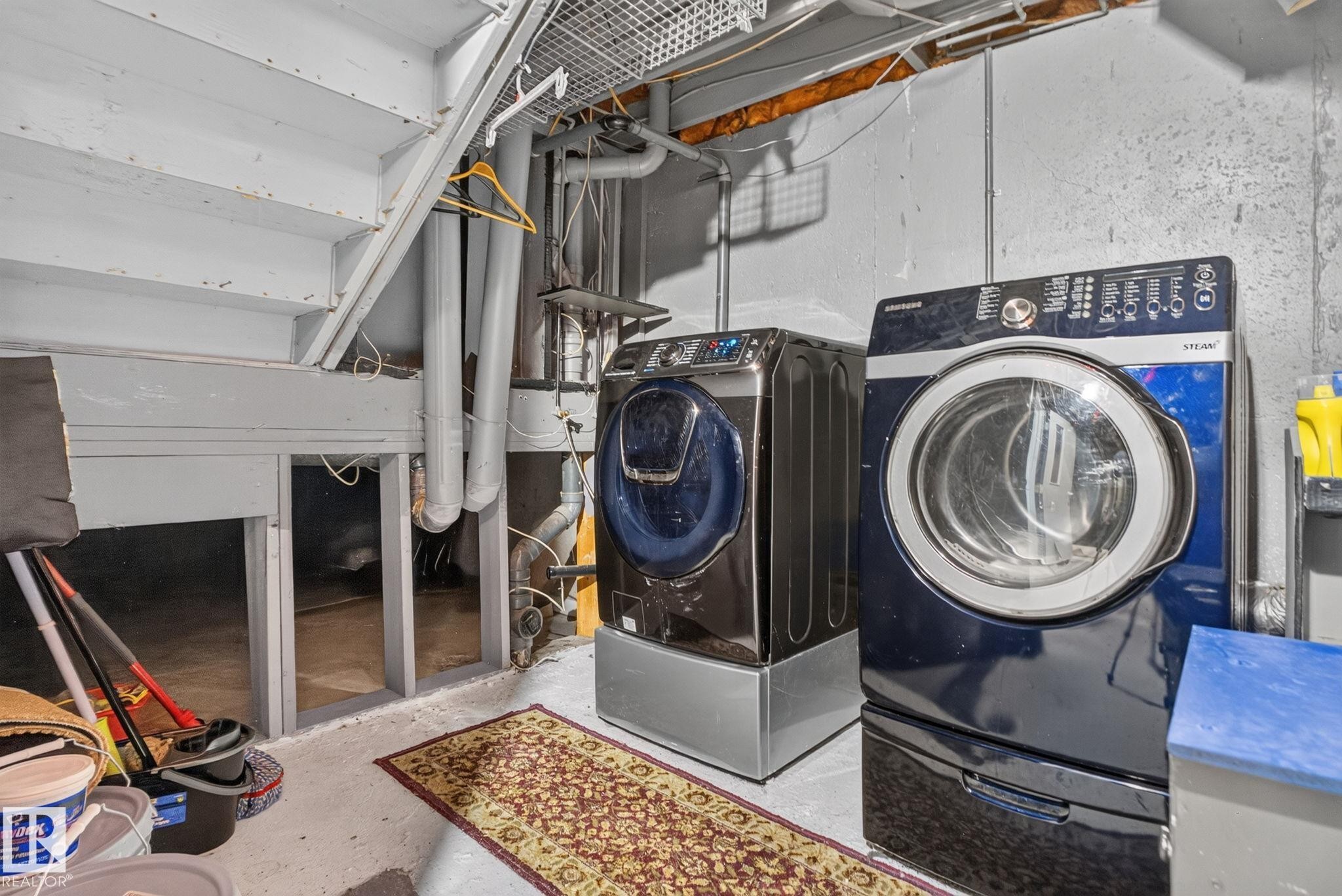 Dedicated laundry area featuring a front-load washer and dryer set, concrete flooring, exposed utility piping, and a wood-framed structural element - 9503 180A Street Nw, Edmonton, AB - Indoor Photo Showing Laundry Room