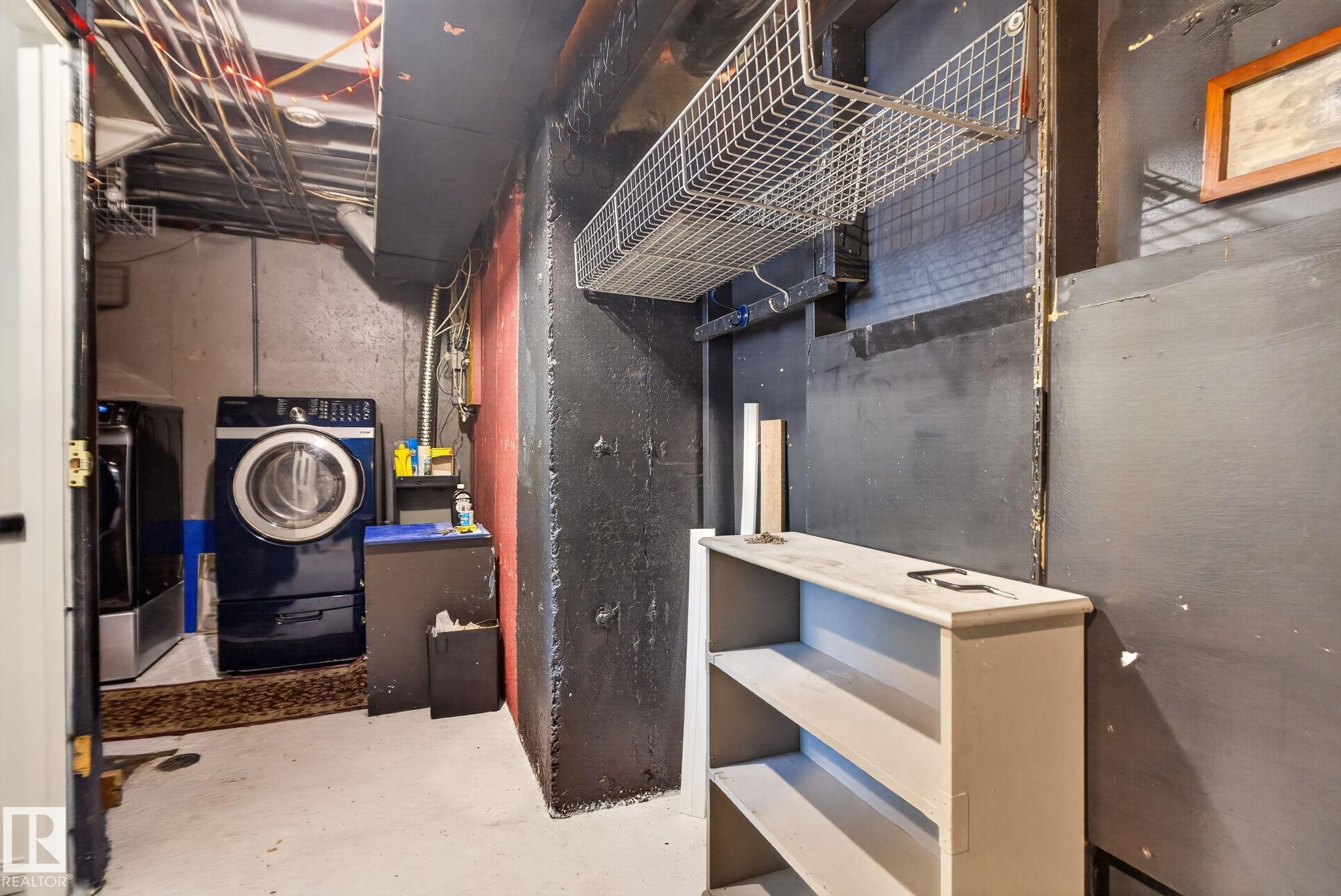 Laundry area with concrete floor, exposed ceiling joists, and built-in shelving - 9503 180A Street Nw, Edmonton, AB - Indoor Photo Showing Other Room