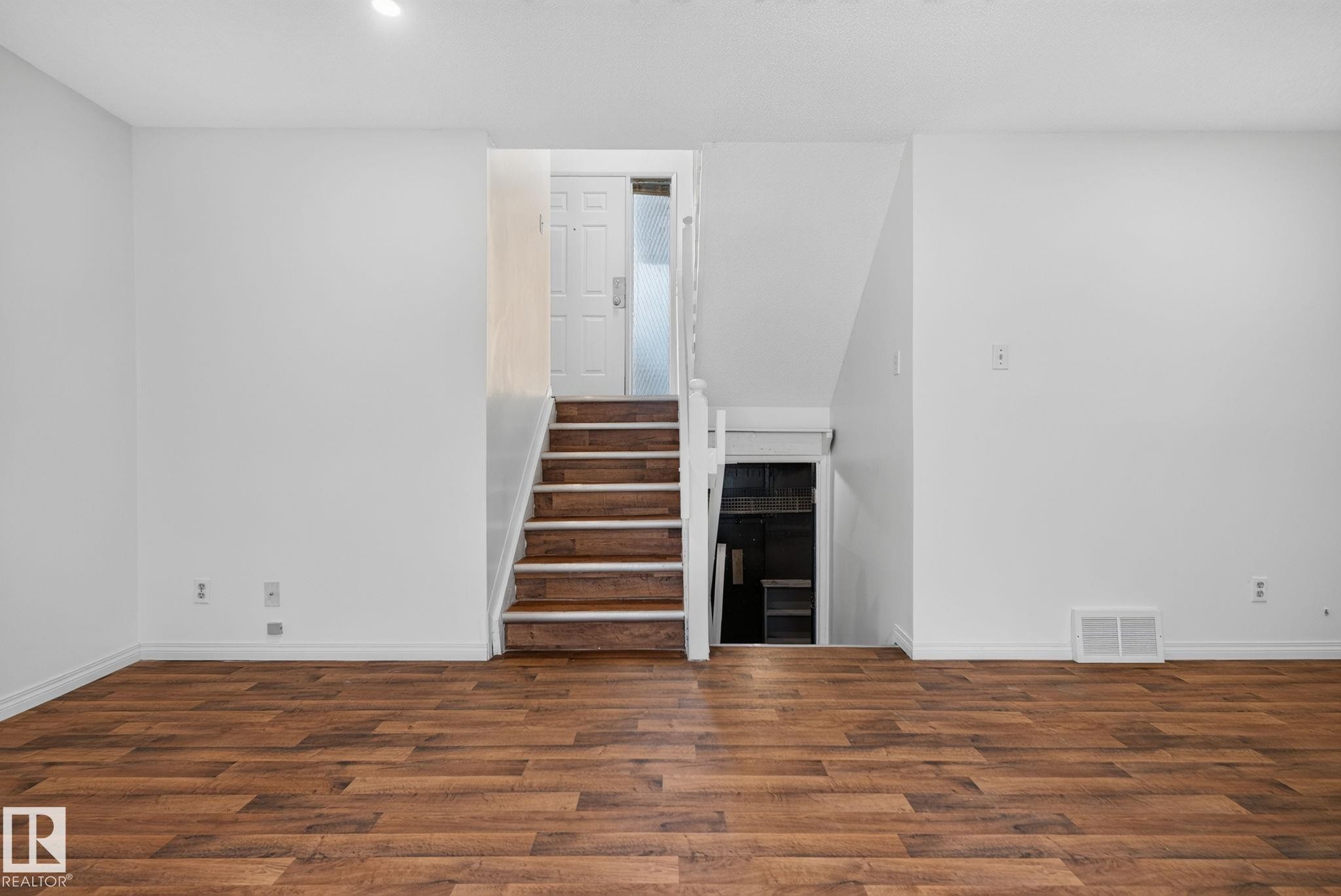 Spacious room featuring wood-finish flooring, white baseboards, and white walls - 9503 180A Street Nw, Edmonton, AB - Indoor Photo Showing Other Room