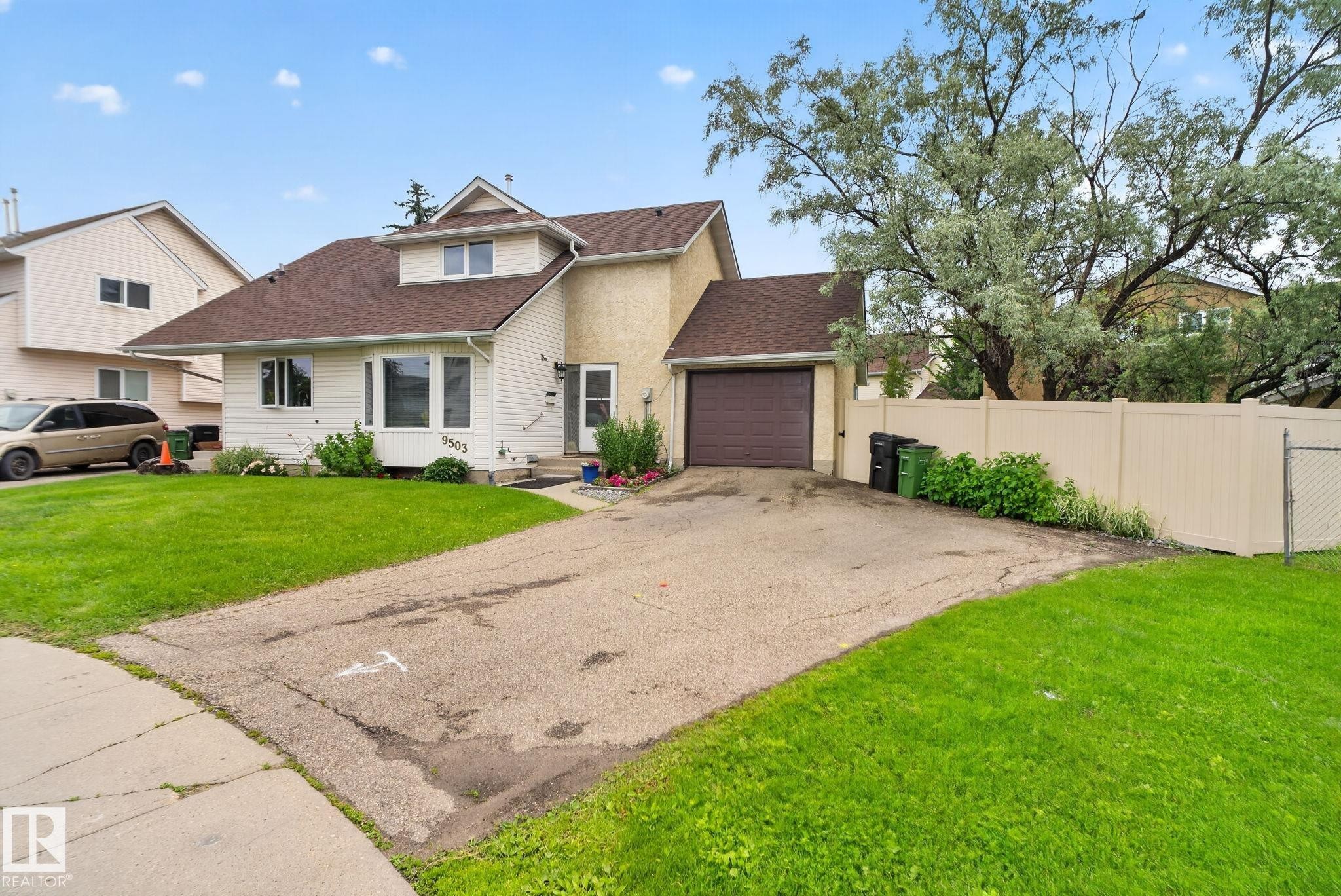 Exterior featuring a concrete driveway, attached single-car garage, and a light-colored privacy fence - 9503 180A Street Nw, Edmonton, AB - Outdoor