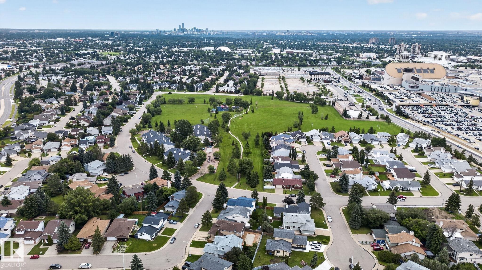 Aerial capturing a suburban residential area with tree-lined streets and a central green space - 9503 180A Street Nw, Edmonton, AB - Outdoor With View