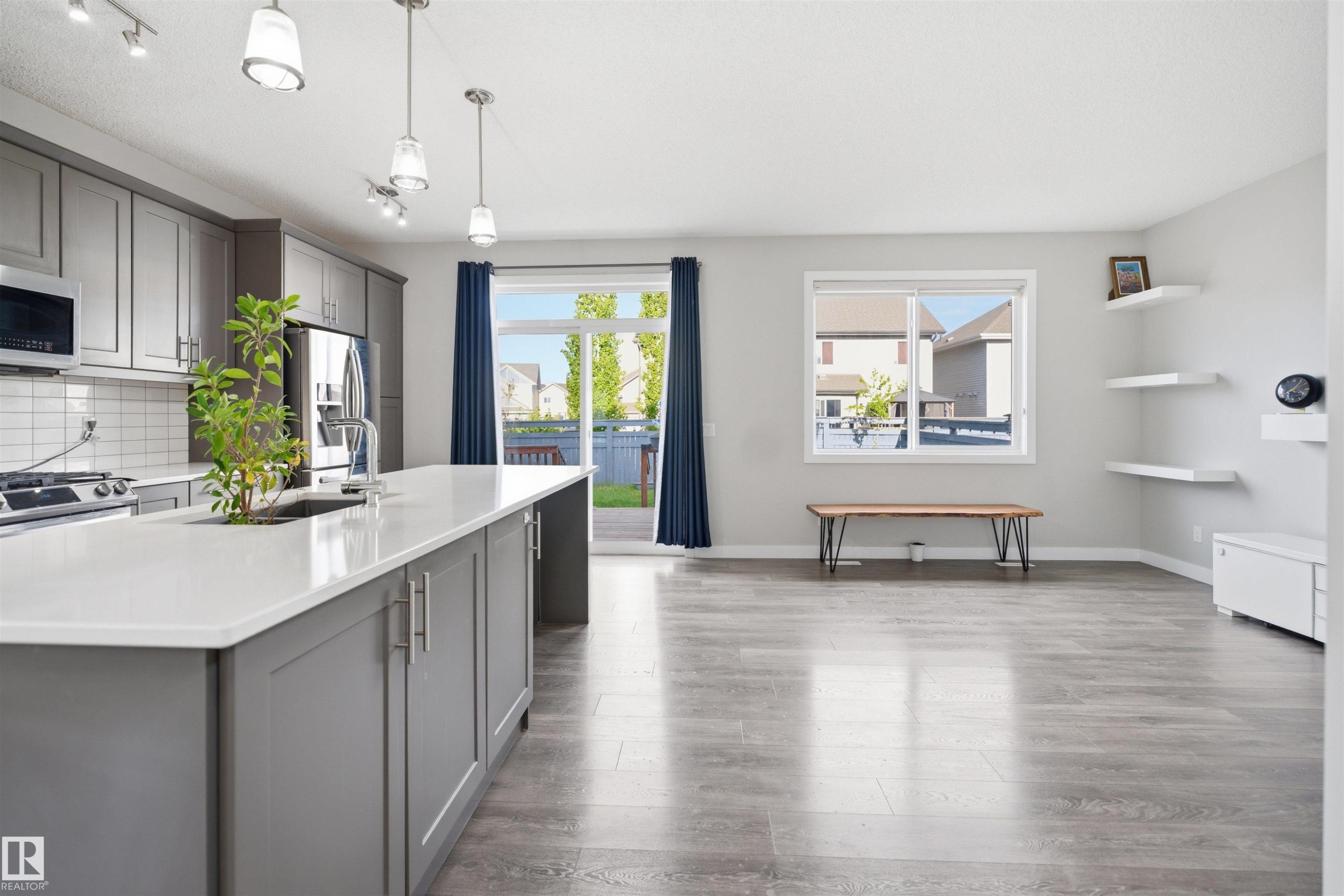 Open-concept living space featuring wood-finish flooring and light gray walls - 1234 Daniels Crescent, Edmonton, AB - Indoor Photo Showing Kitchen With Upgraded Kitchen